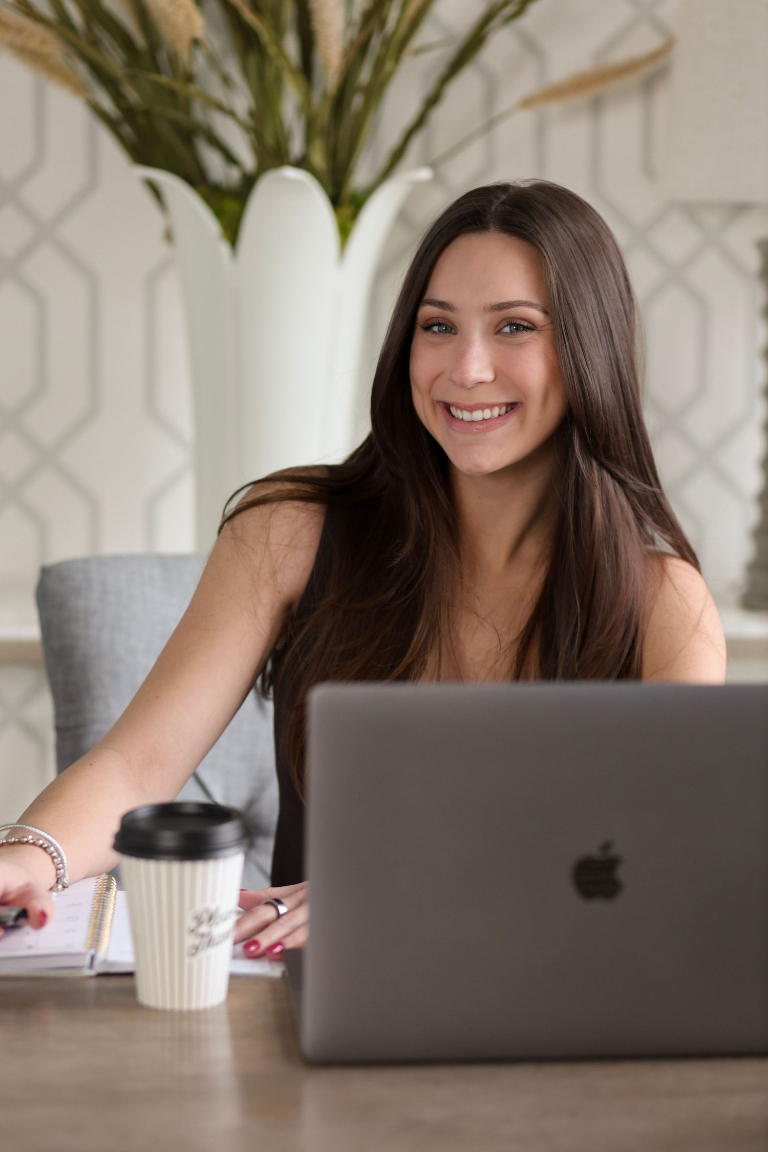 Person working on MacBook laptop with coffee cup in contemporary home office environment.
