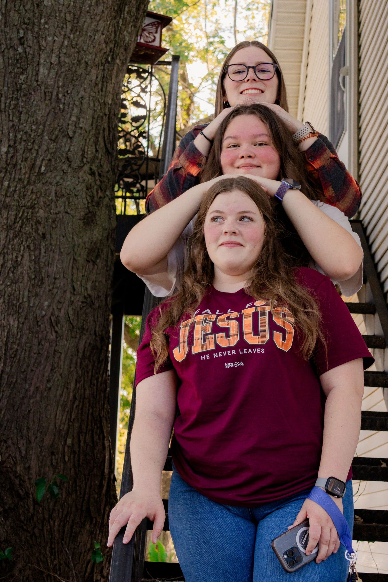 A person in a burgundy t-shirt and jeans poses playfully in a sequence of photos on a porch.