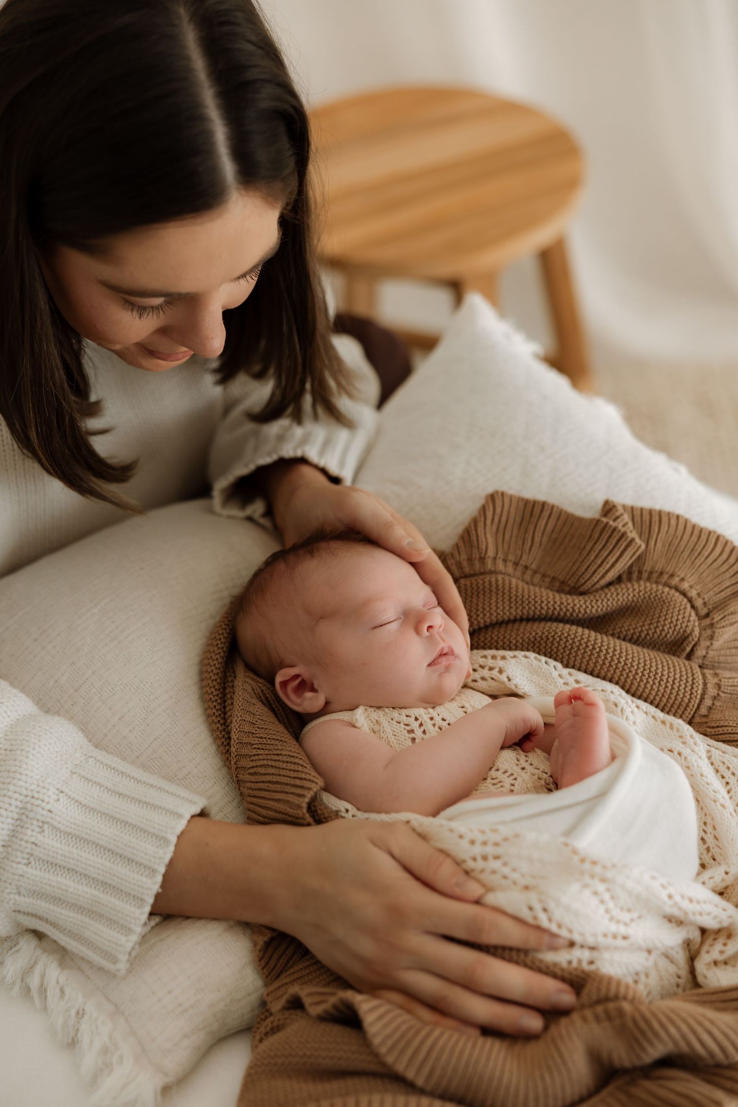 A tender moment between parent and sleeping newborn baby in soft neutral tones.