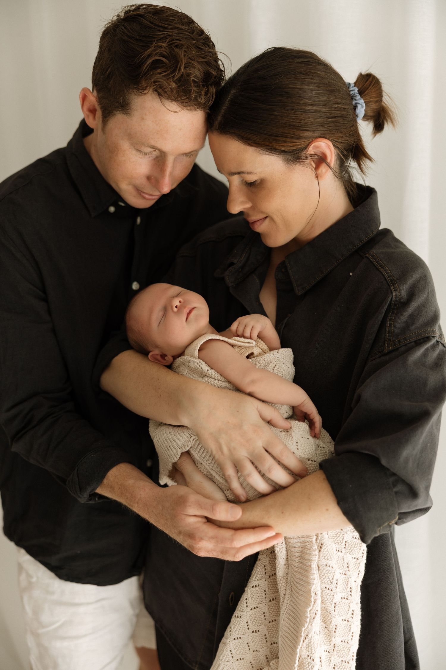 A series of tender black and white photos showing parents cradling and bonding with their newborn baby.