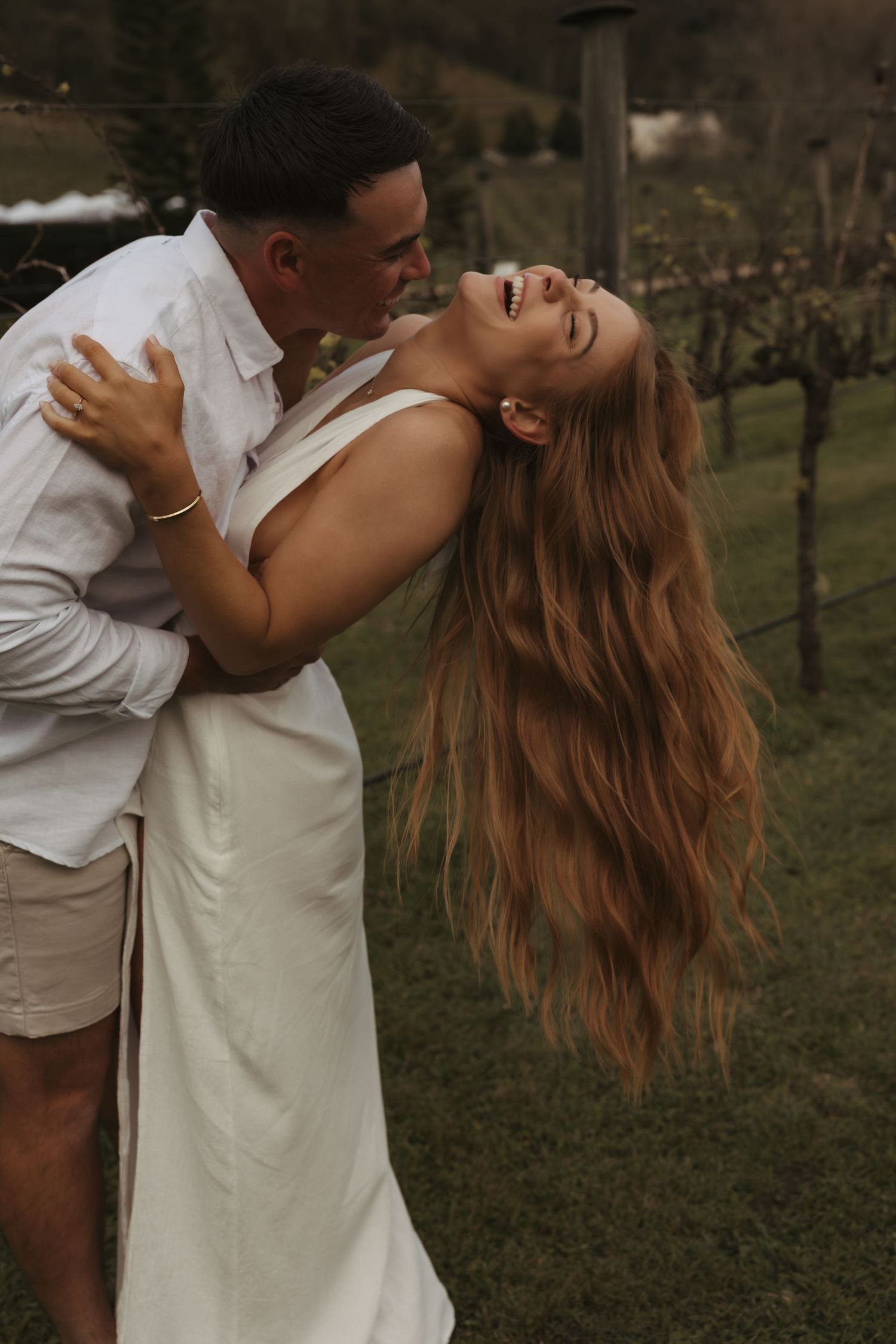 Romantic couple embraces in a garden setting during a warm sunset photoshoot.