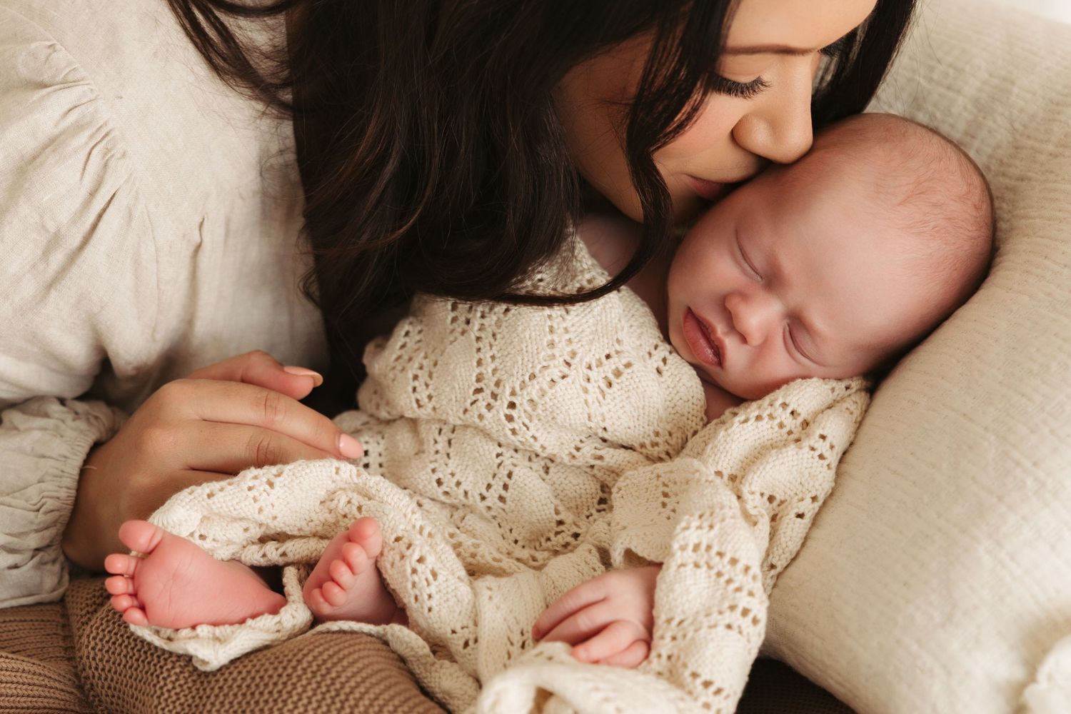 Peaceful newborn sleeping on cream lace blanket during lifestyle photoshoot.
