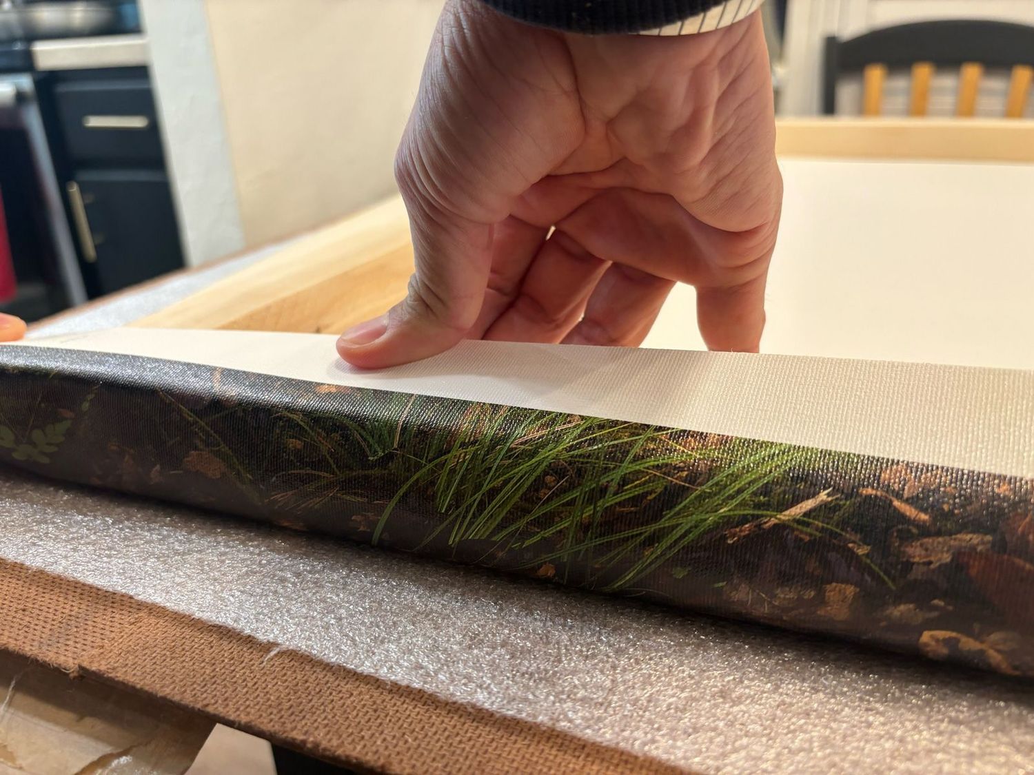 Hands examining the textured edges of a mounted canvas print.