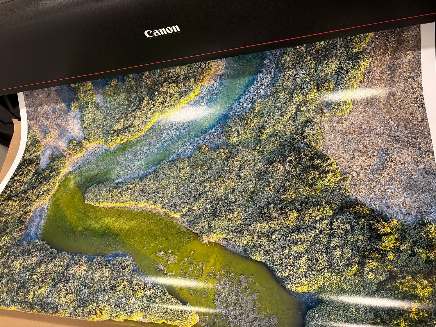 Aerial landscape photograph showing winding river and lush green terrain being printed. Printed in Escaype Print Lab in Marin County, CA.