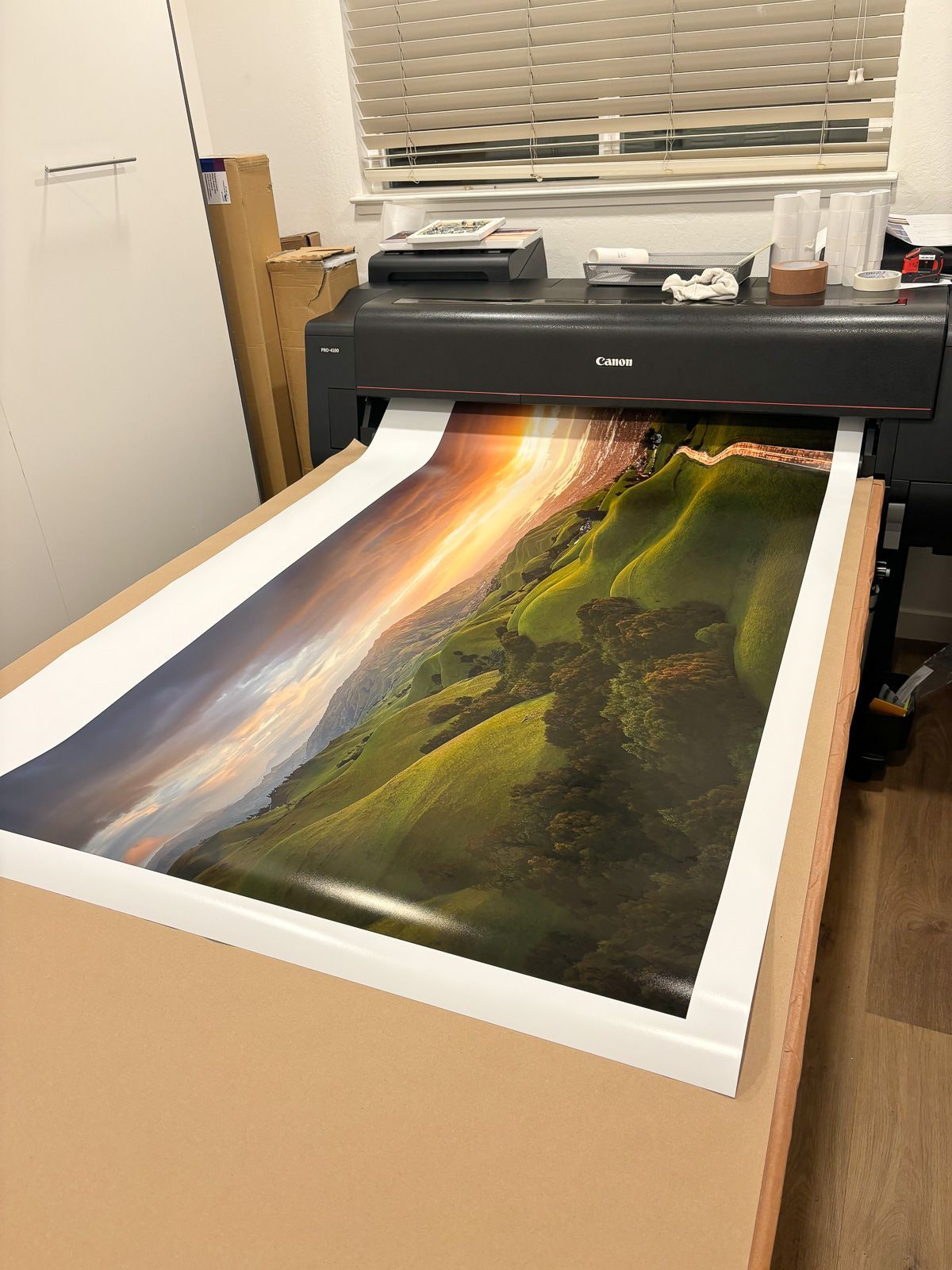 Large format Canon printer producing a vibrant landscape print with dramatic lighting and mountain scenery. Interior of Escaype Print Lab.