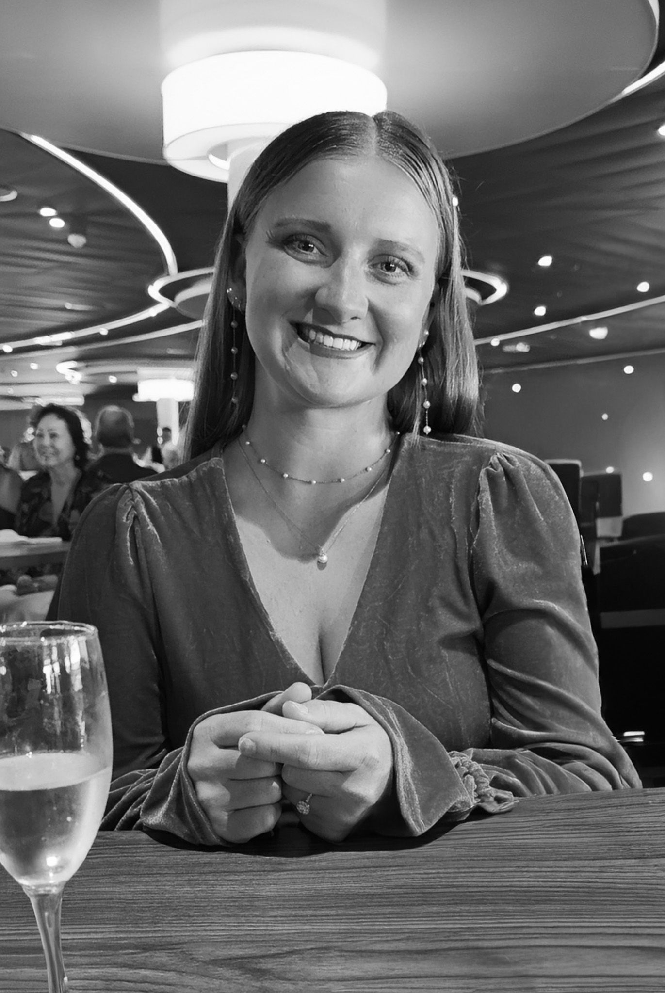 Person sitting at a restaurant table with a wine glass in a dimly lit setting.