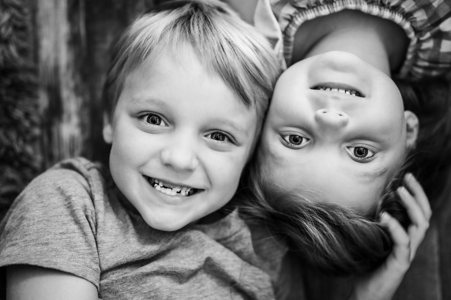 Close up black and white portrait of two playful children with one upside down.