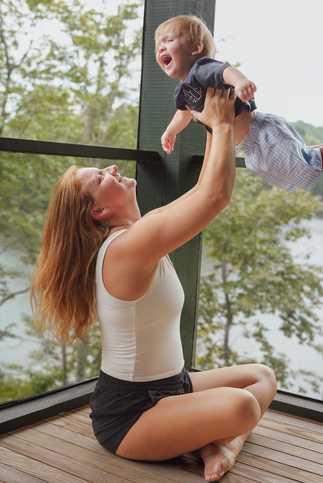 Joyful moment captured as parent lifts laughing child high in sunlit room.