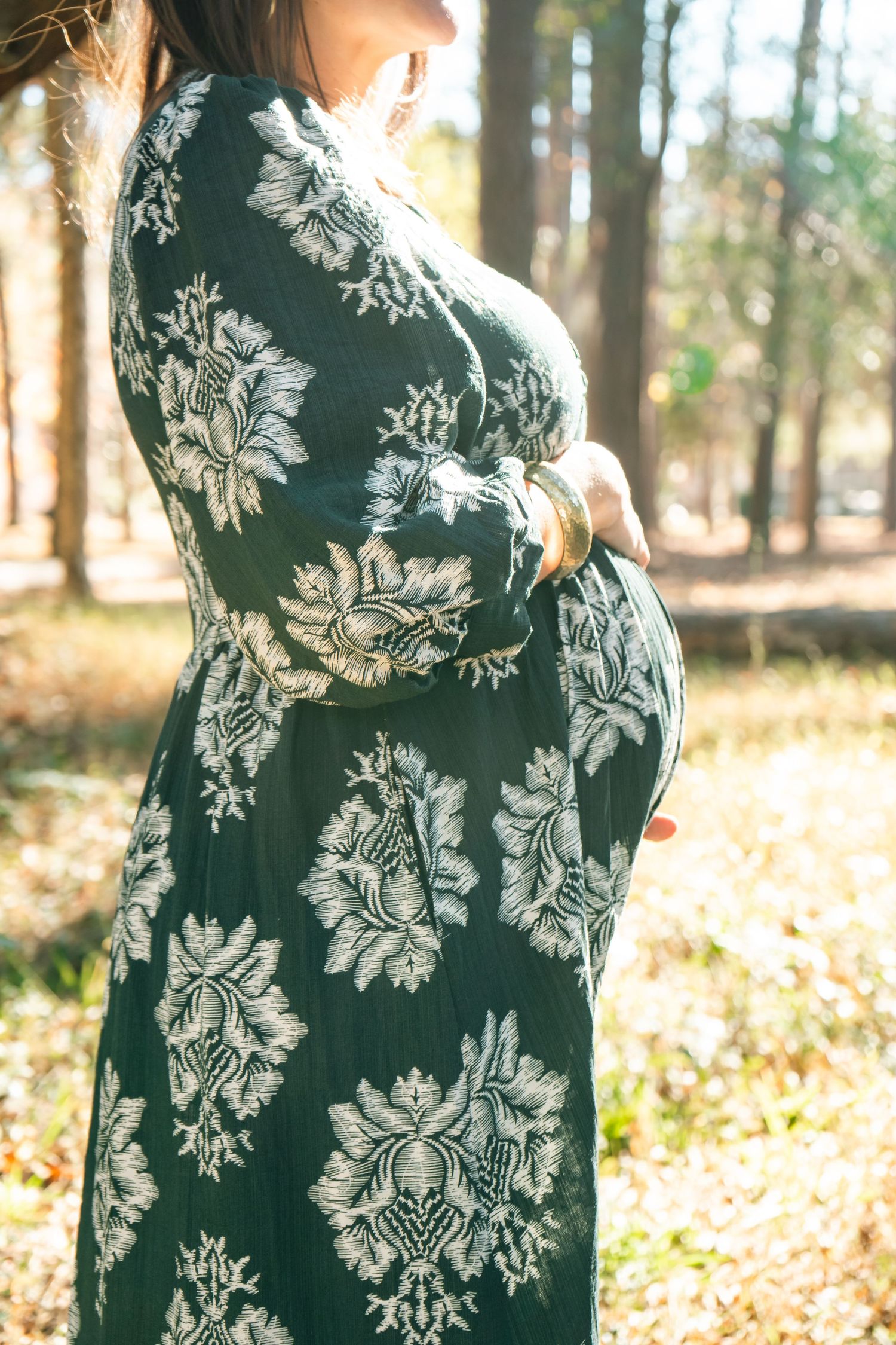 A green dress with white floral patterns shown in multiple angles against a sunlit forest background.