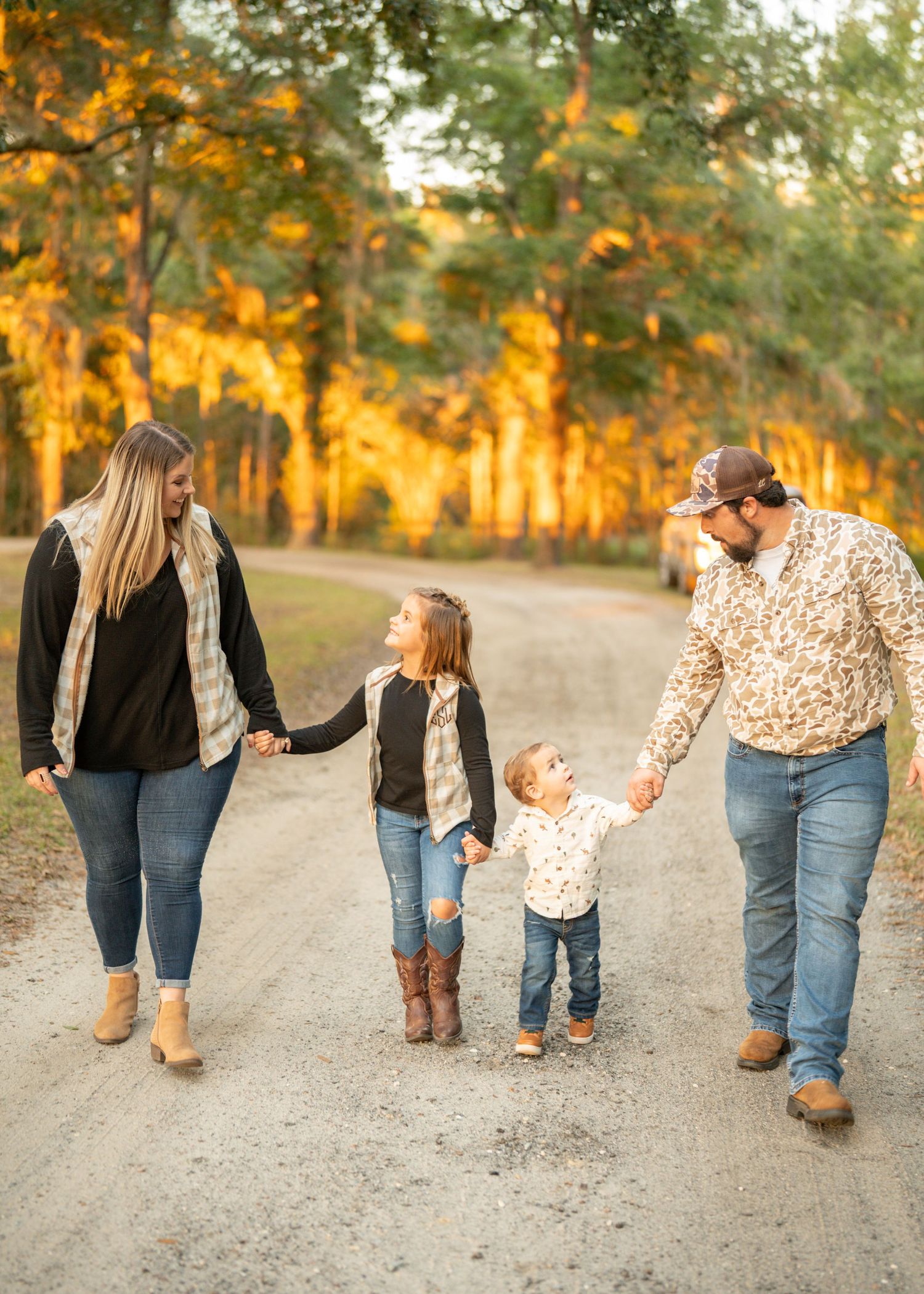 Family walking together on dirt path at sunset wearing casual denim and leopard print outfits.