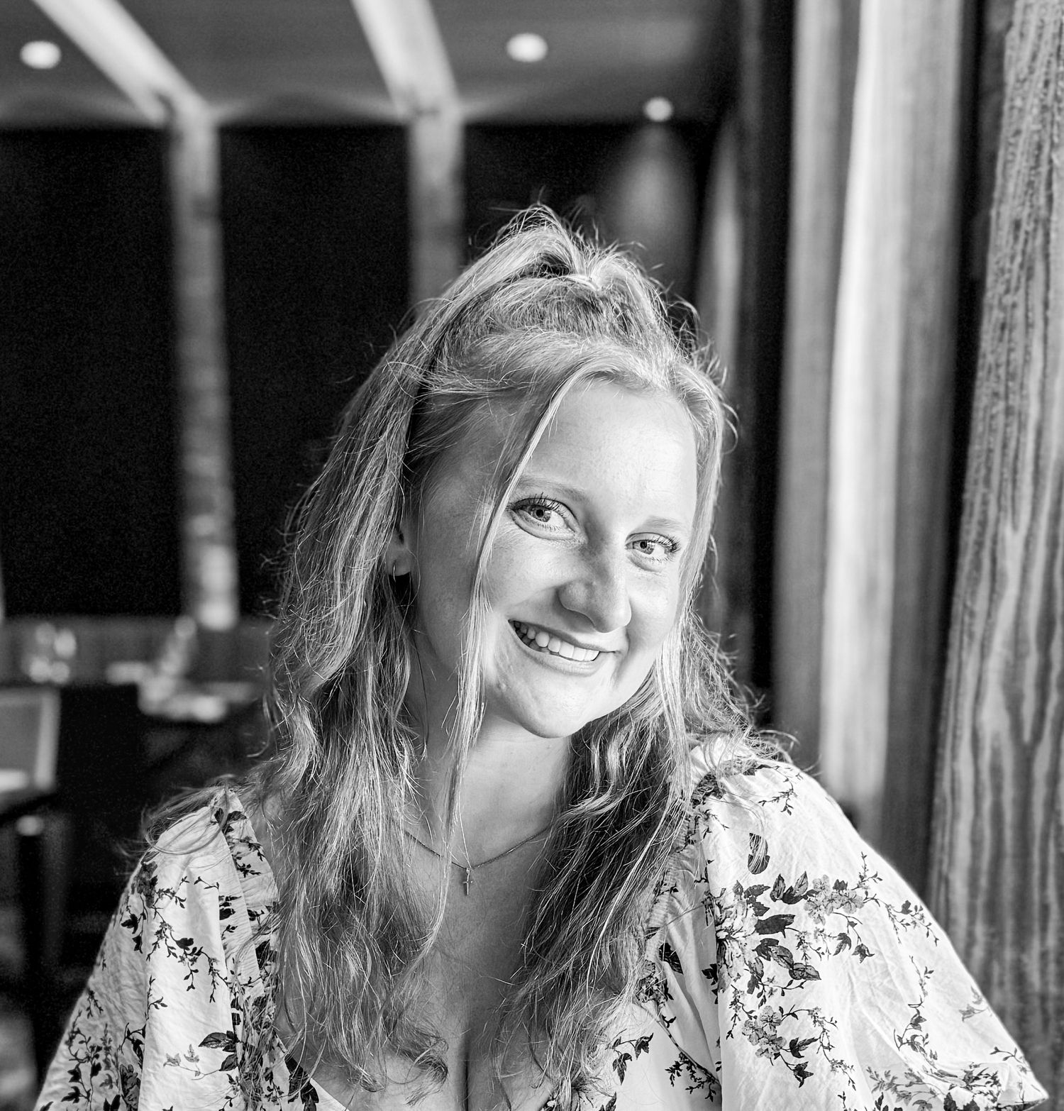 Black and white candid portrait showing someone smiling in restaurant setting.