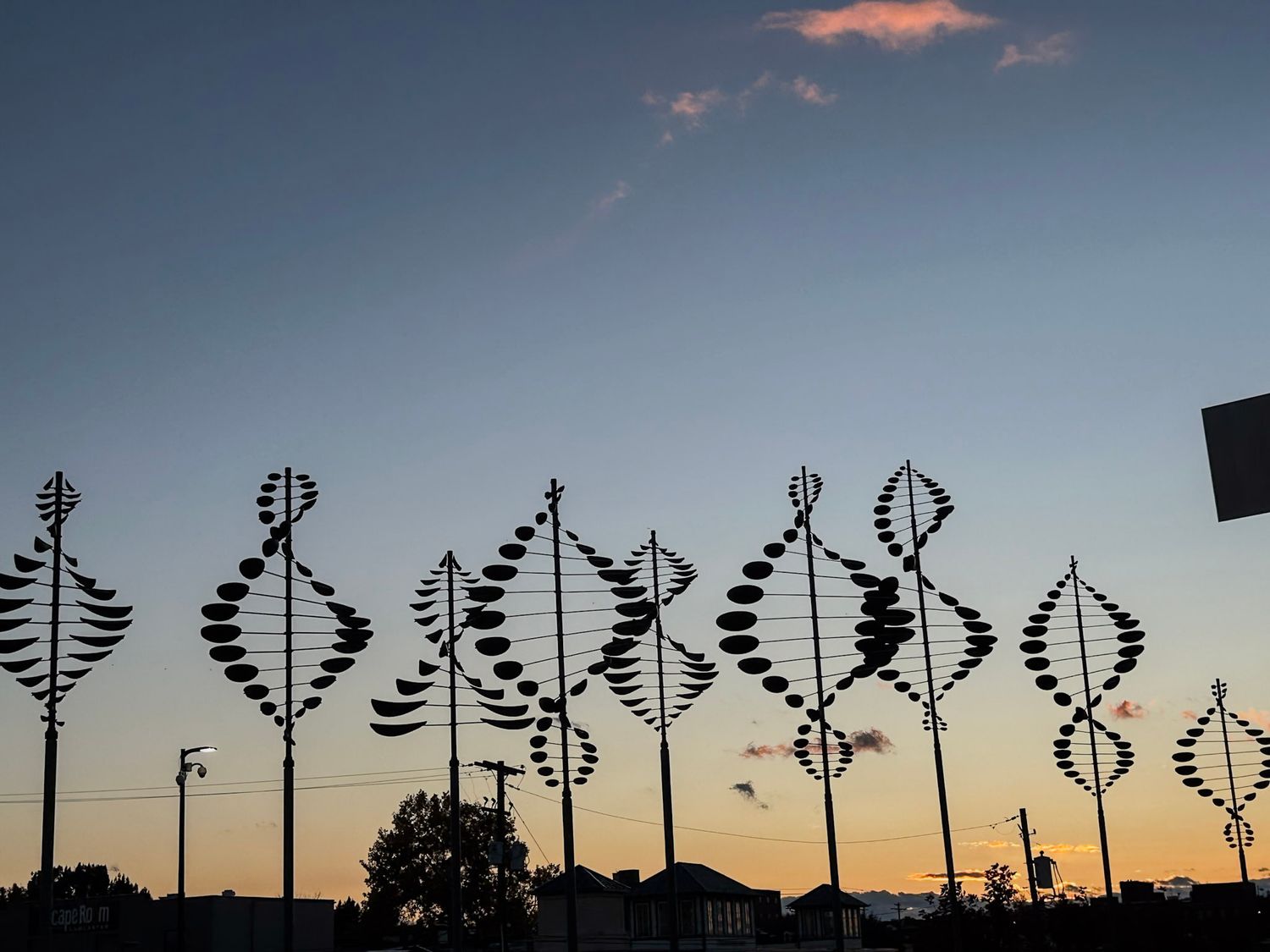 Silhouettes of artistic metal sculptures against a sunset sky creating a decorative skyline.