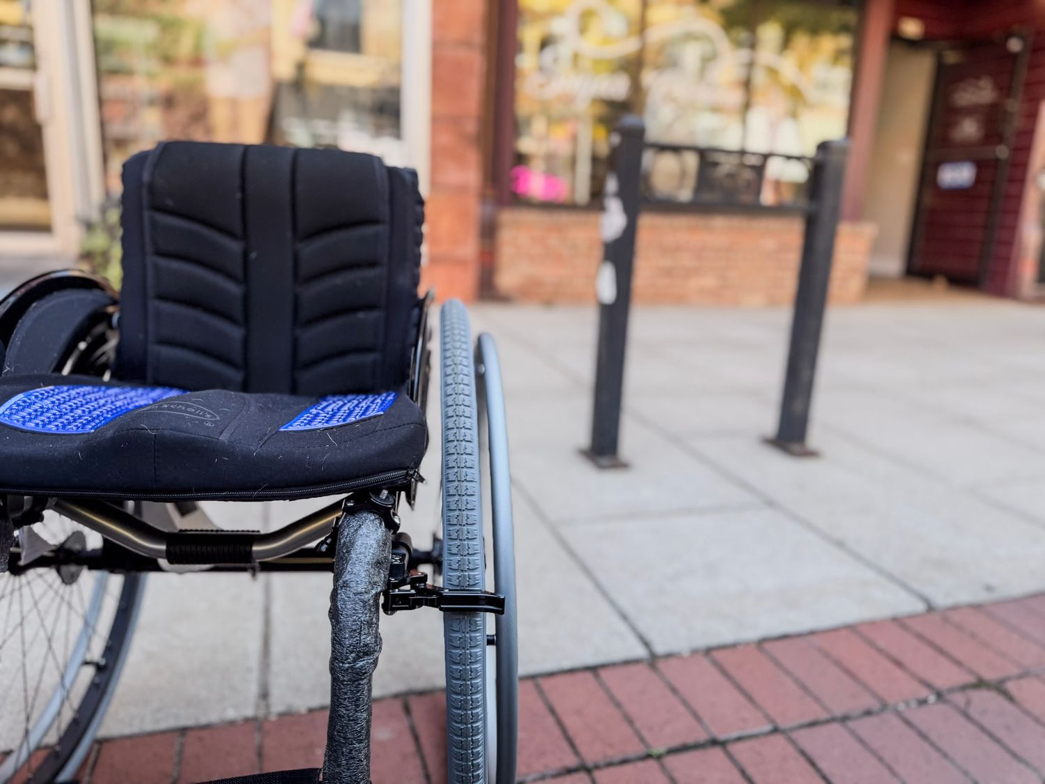 Wheelchair accessibility features including ramps and handrails along a brick sidewalk.