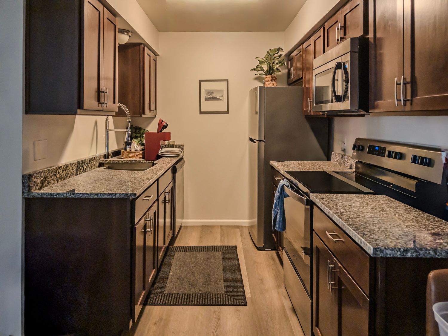 Modern kitchen with dark cabinets, granite countertops, and stainless steel appliances.