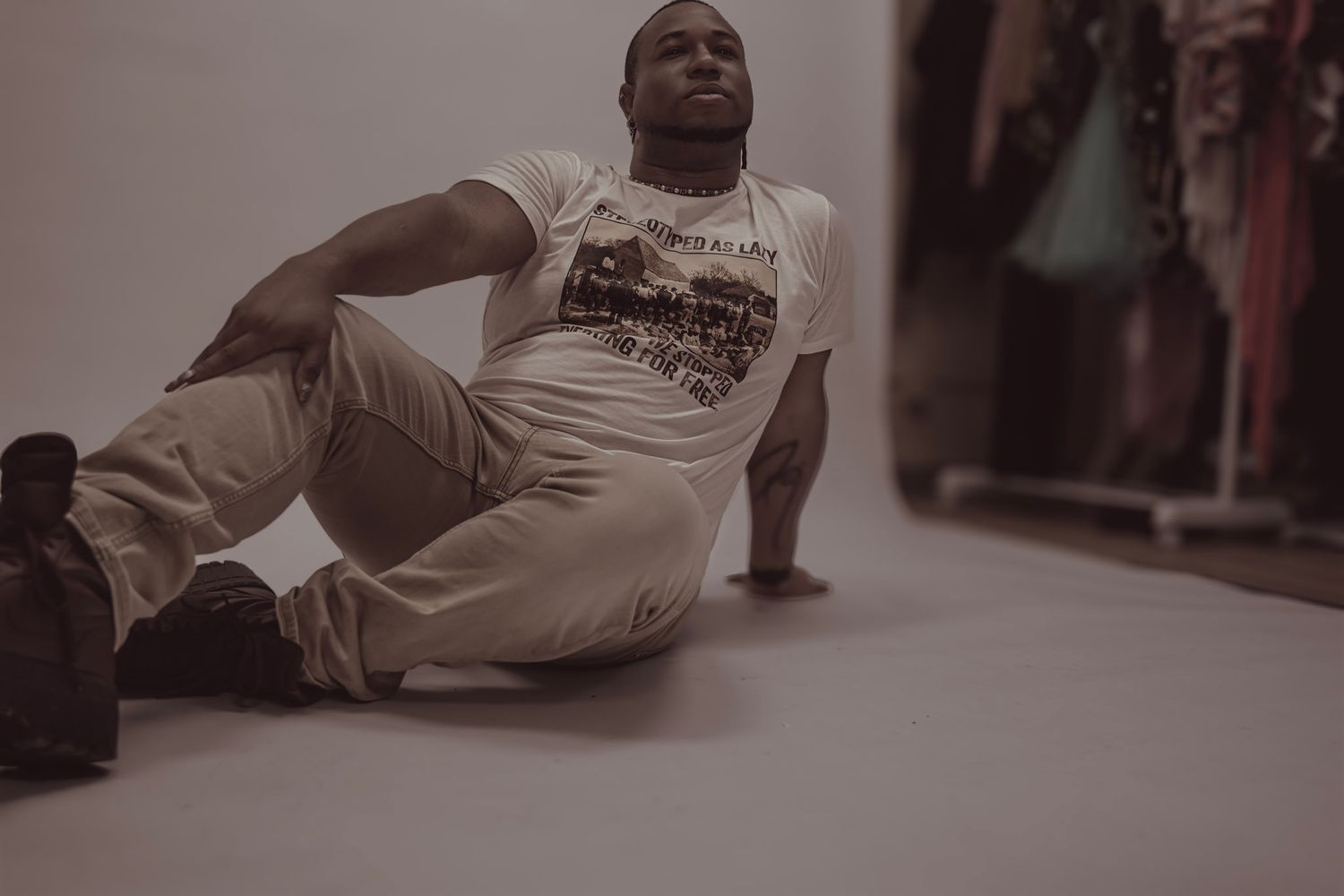 A person in white clothing lies on the floor in what appears to be a performance or artistic pose.