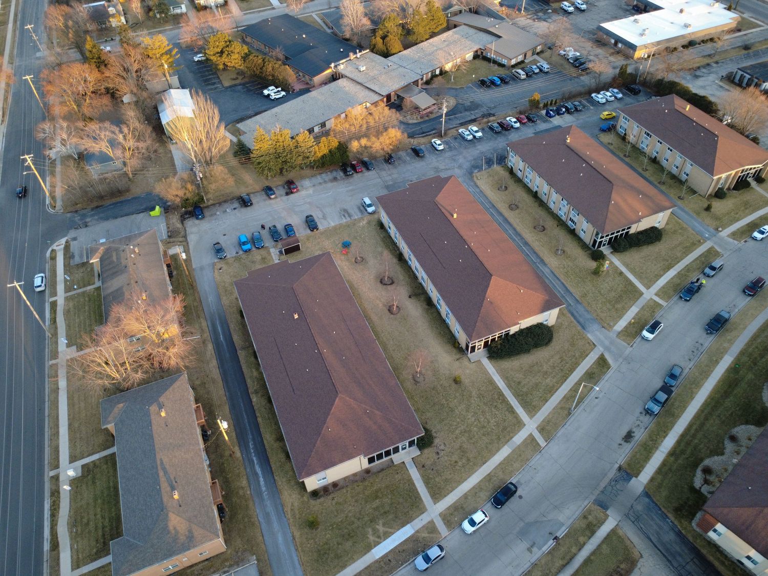 Aerial view of suburban neighborhood with autumn trees and residential buildings along winding roads.