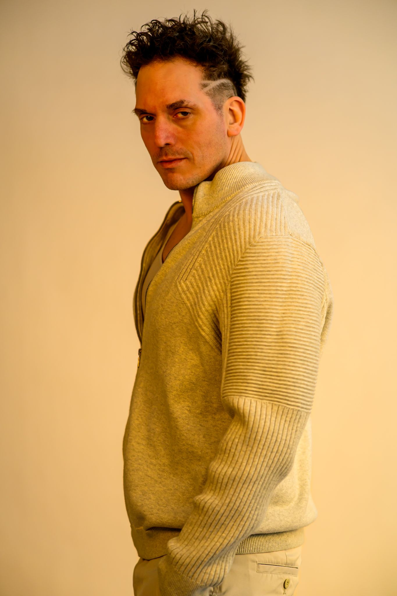 A series of profile shots showing someone wearing a beige knit sweater against a cream-colored background.