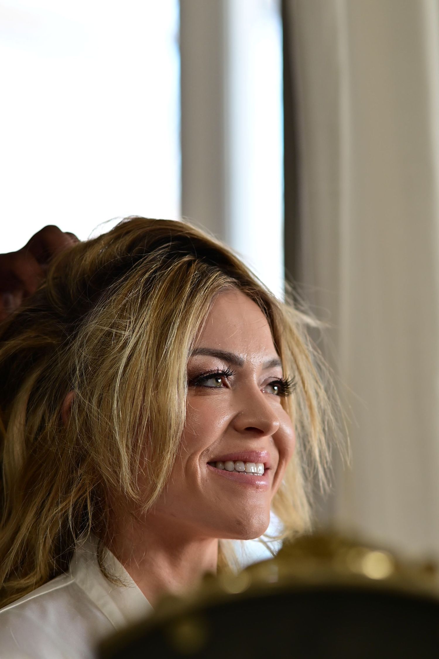 A woman with blonde hair smiles while looking up in a sequence of profile shots with soft lighting.