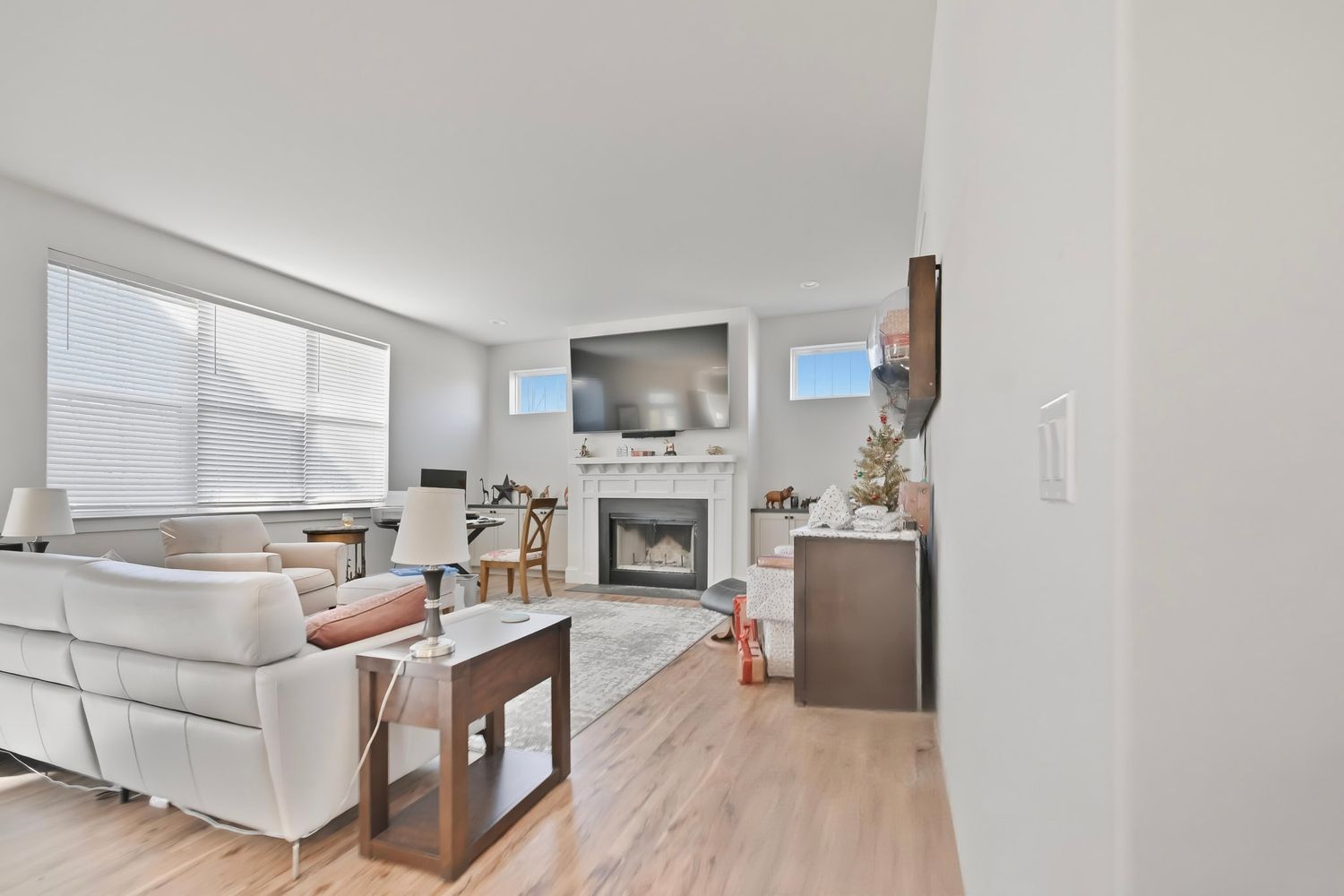 Modern open concept apartment interior with white kitchen cabinets, hardwood floors and stainless steel appliances.