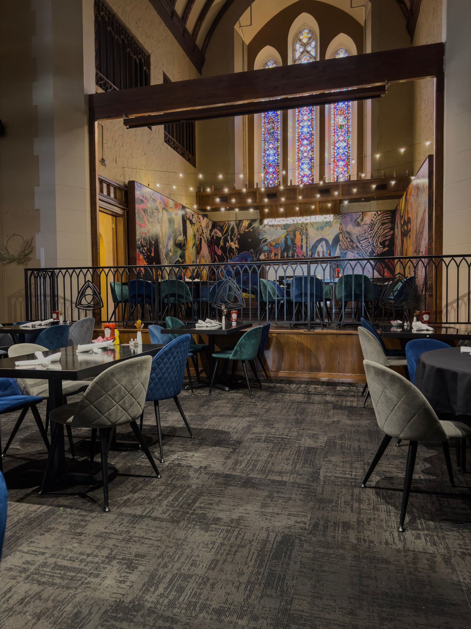 Large dining hall with blue accents and string lights in converted church space.