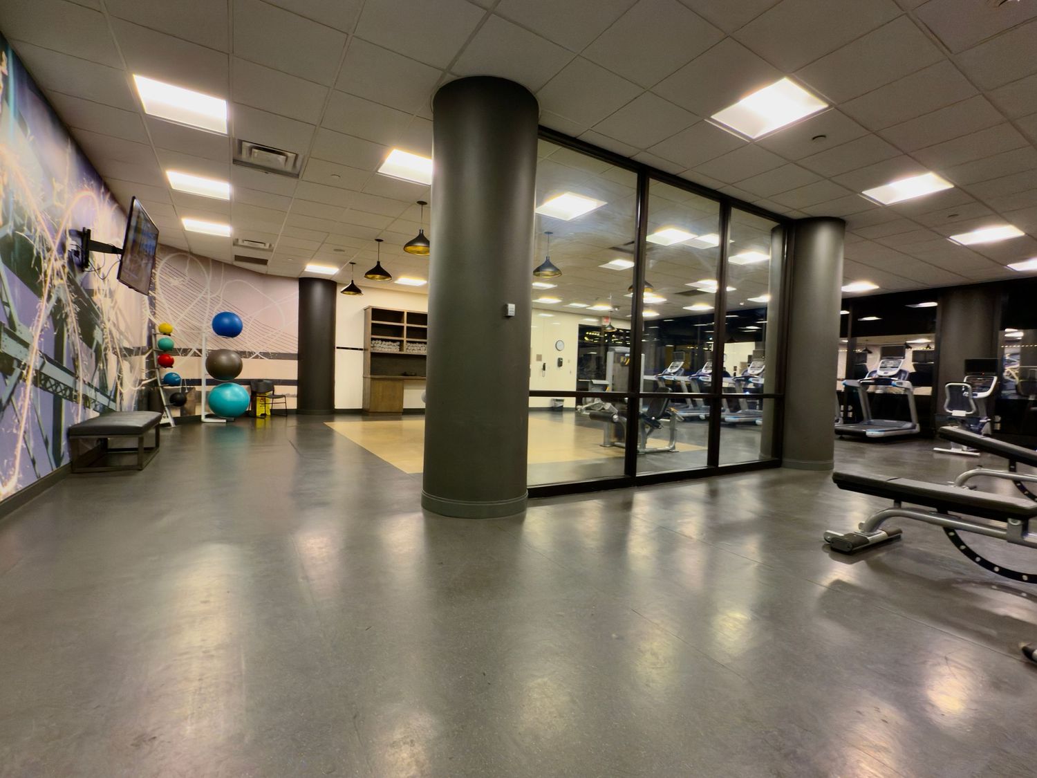 A series of connected images showing a modern fitness center with exercise equipment and fluorescent lighting.