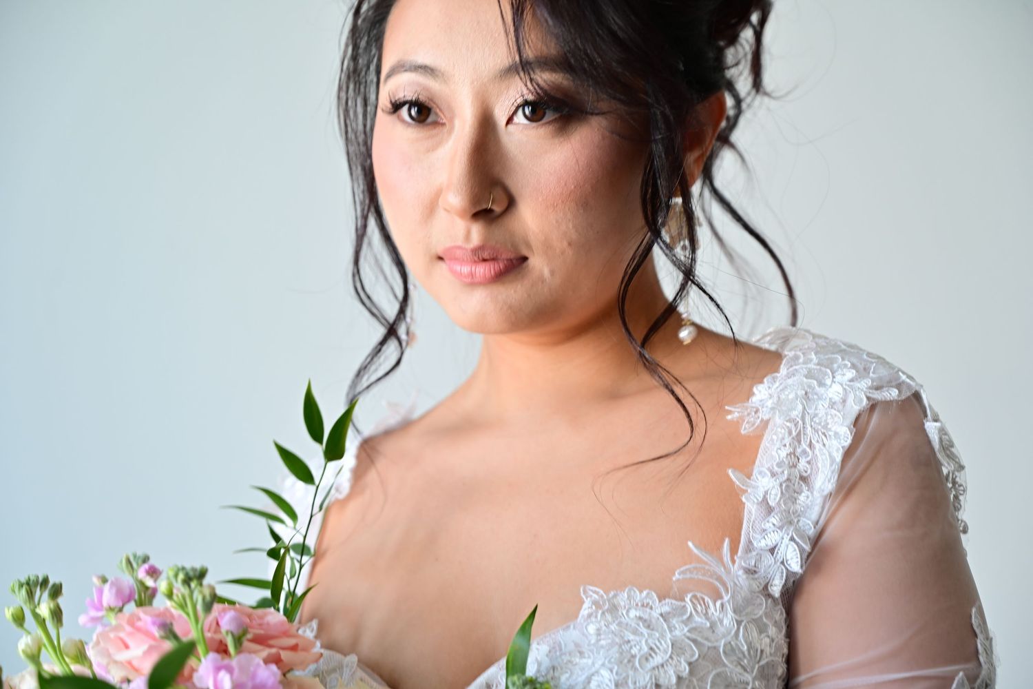 A person wearing a delicate white lace wedding dress poses elegantly in a bridal portrait session.