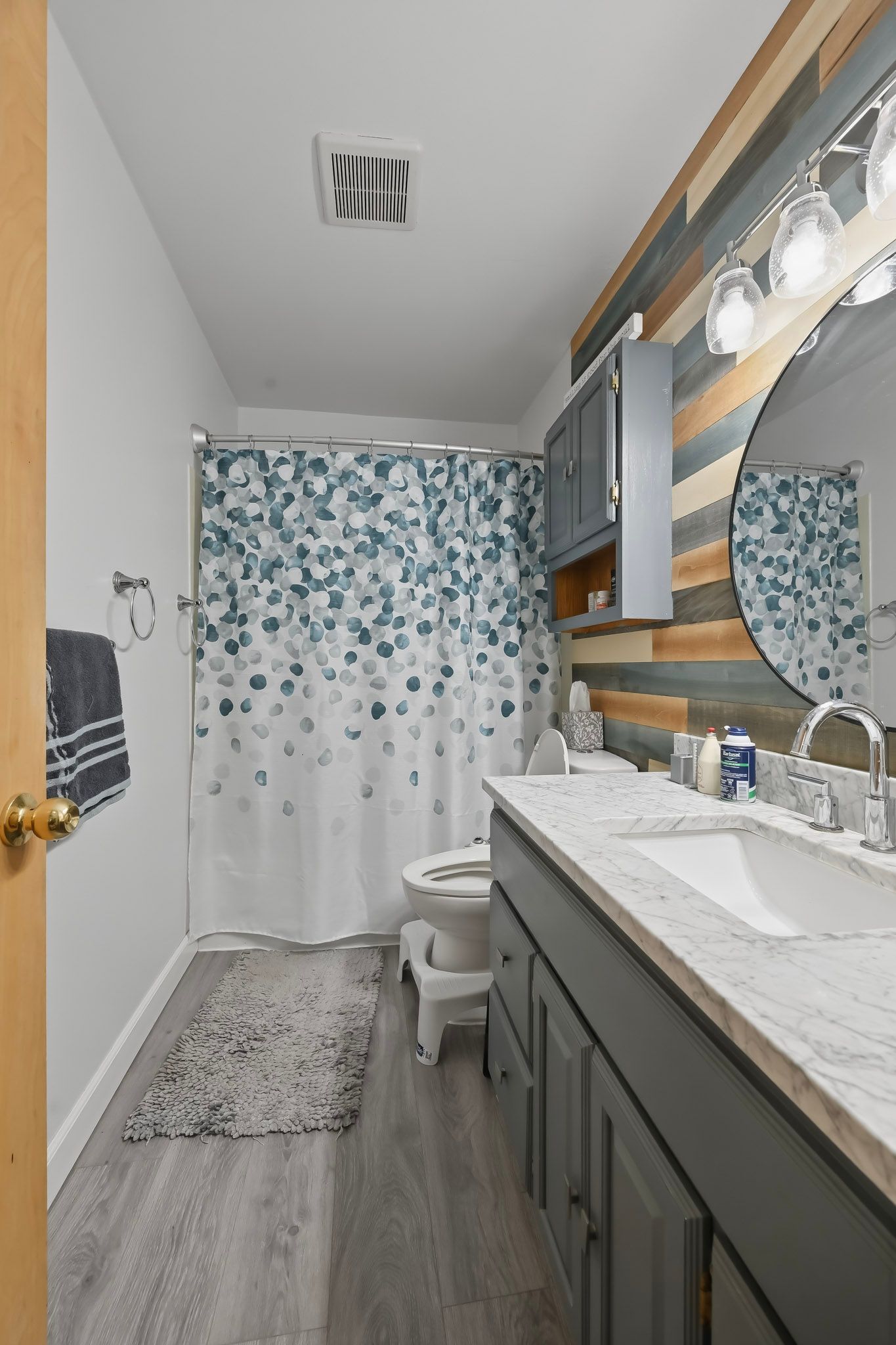 Spacious bathroom with gray flooring, blue bubble wall decor, and long vanity with bright lighting.