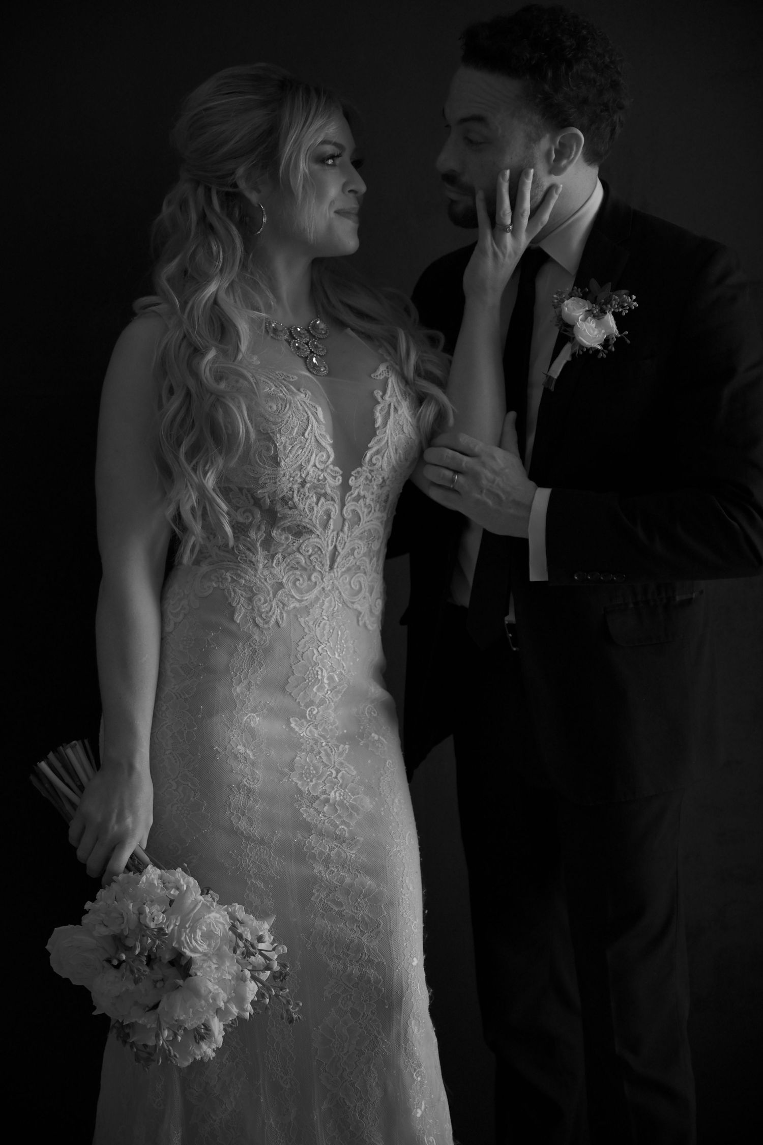 A romantic black and white wedding photo showing a couple in formal attire sharing an intimate moment.