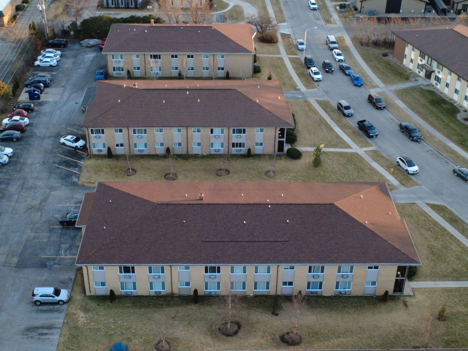 Aerial view of apartment complexes and parking lots in a residential neighborhood on a cloudy day.