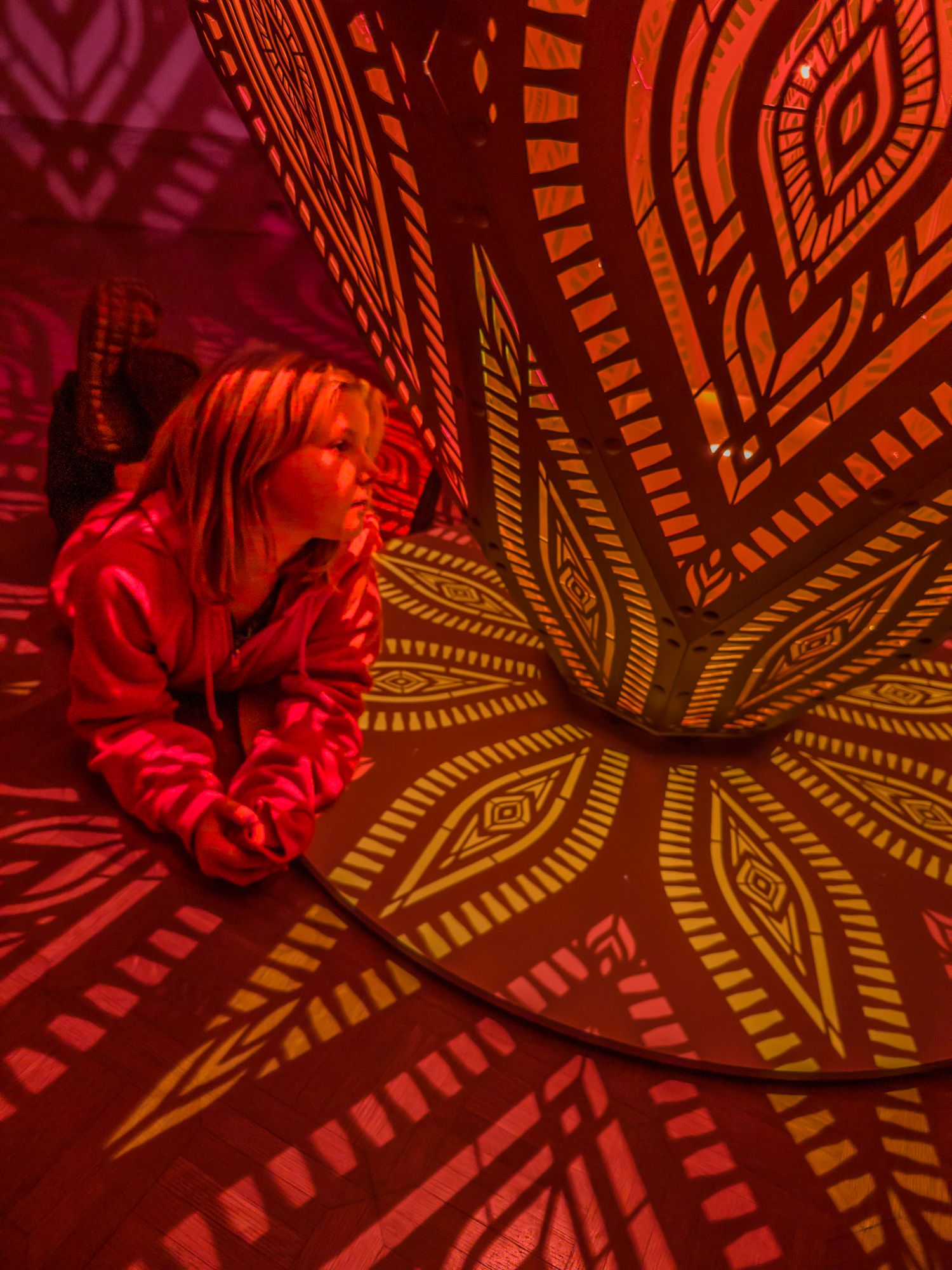 Abstract red and gold geometric patterns casting shadows on a surface.