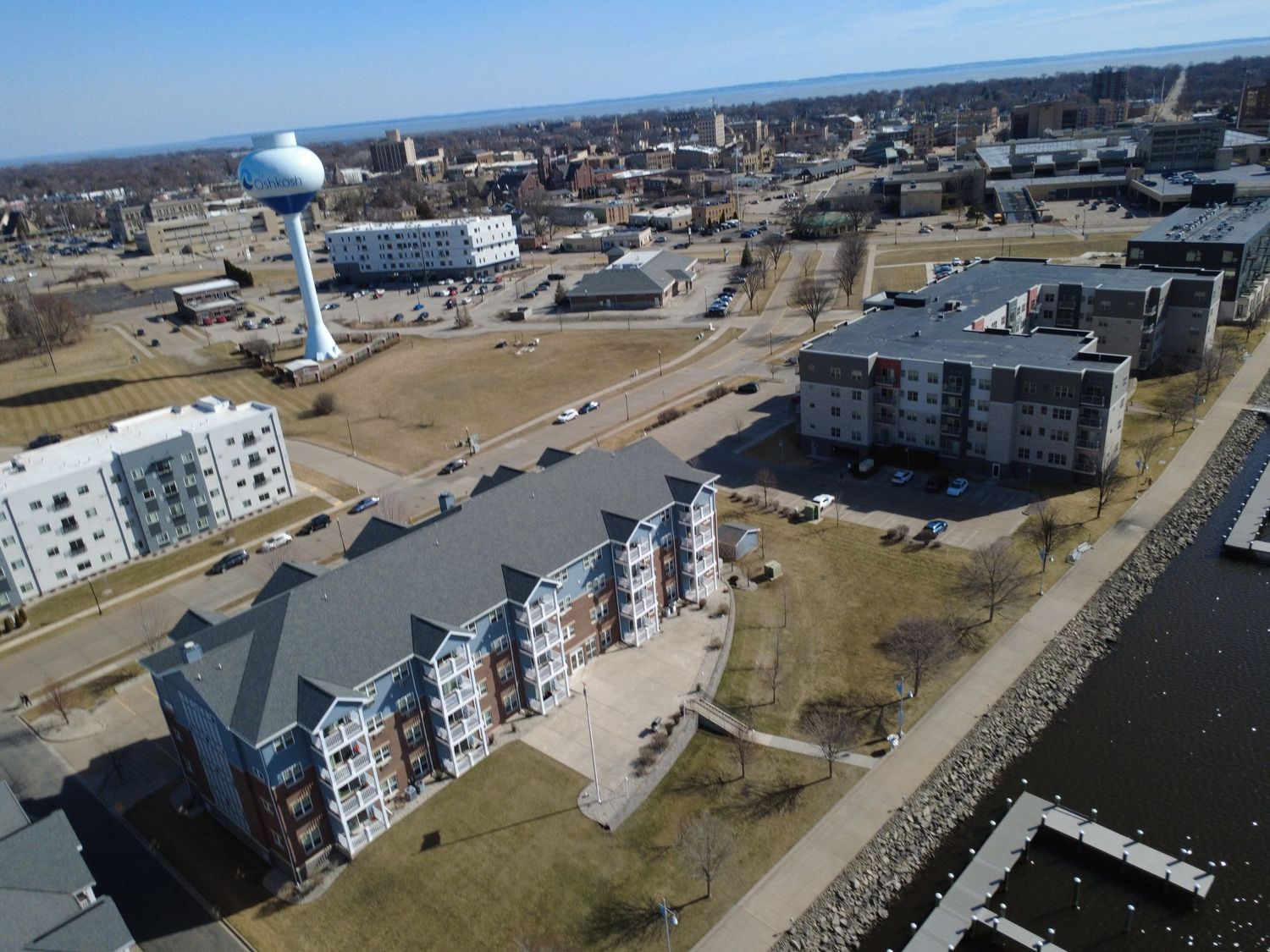 Aerial drone view of coastal apartment buildings and waterfront developments along a shoreline.