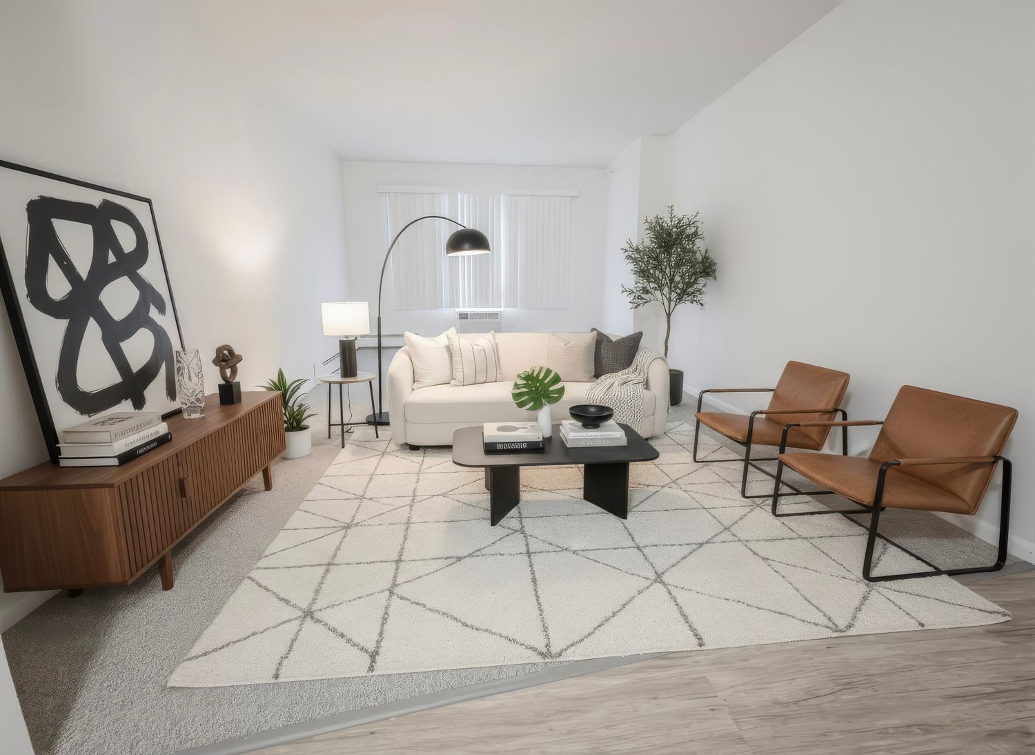Modern minimalist living room interior with geometric rug, leather chairs, and abstract wall art in neutral tones.