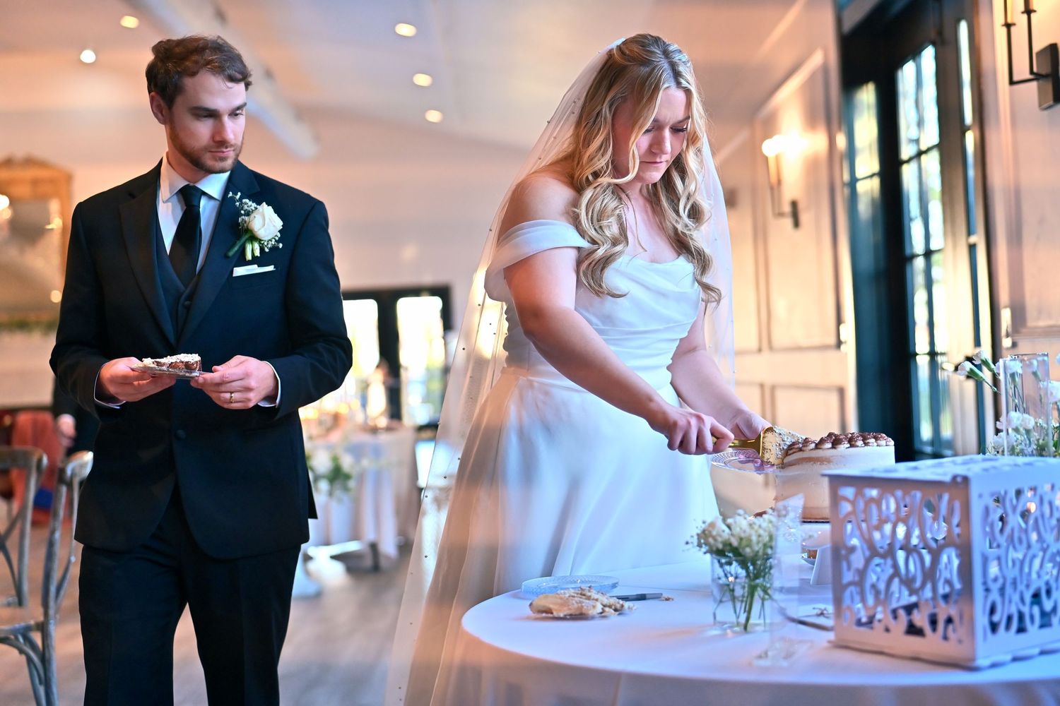 Bride and groom performing a wedding unity ceremony at an elegant indoor venue with white decor.