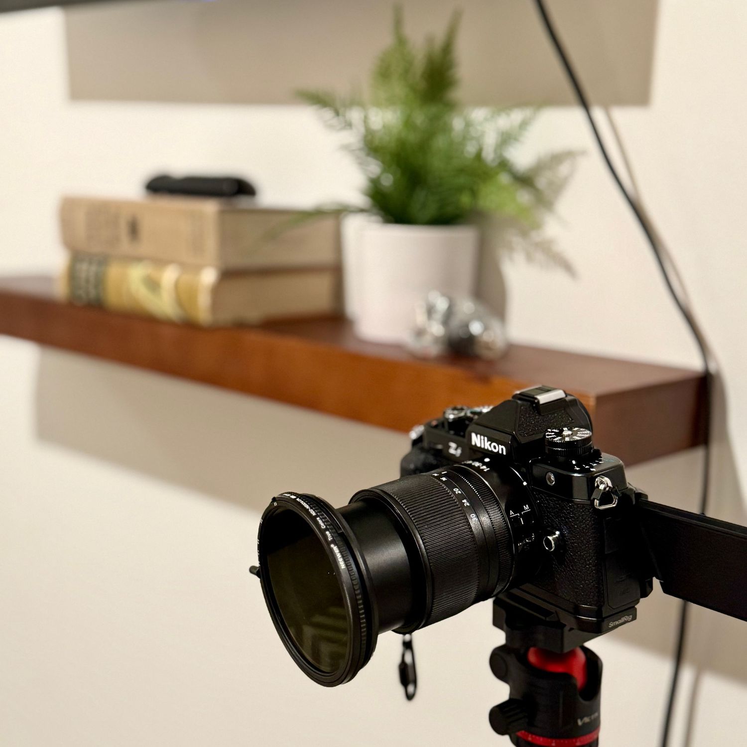 Close-up view of a black DSLR camera lens with a blurred background showing camera equipment.
