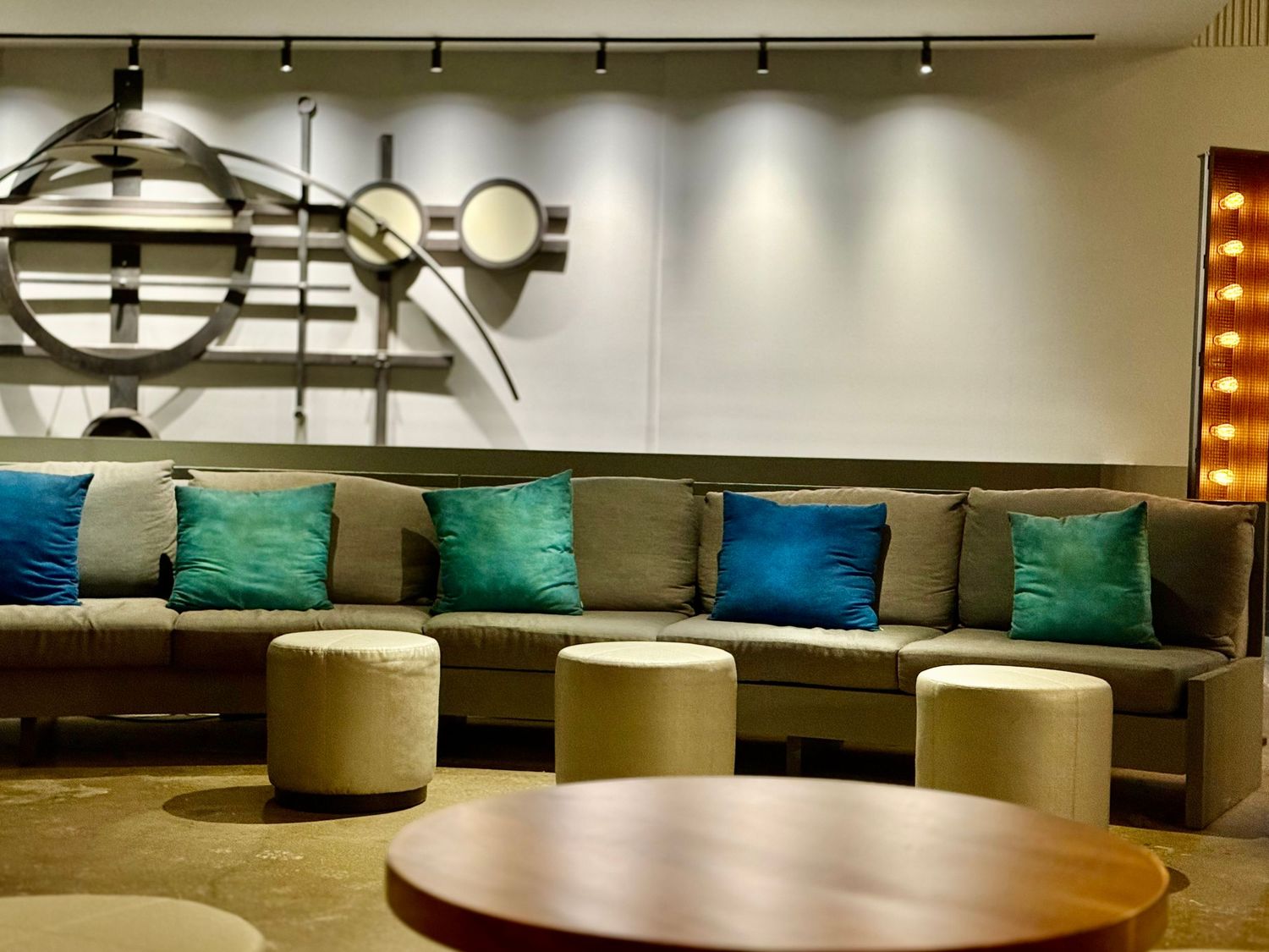 Modern restaurant booth seating with colorful blue and teal throw pillows against a dark wall with track lighting.