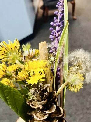 Close-up of yellow dandelions and purple flowers in a rustic floral arrangement.