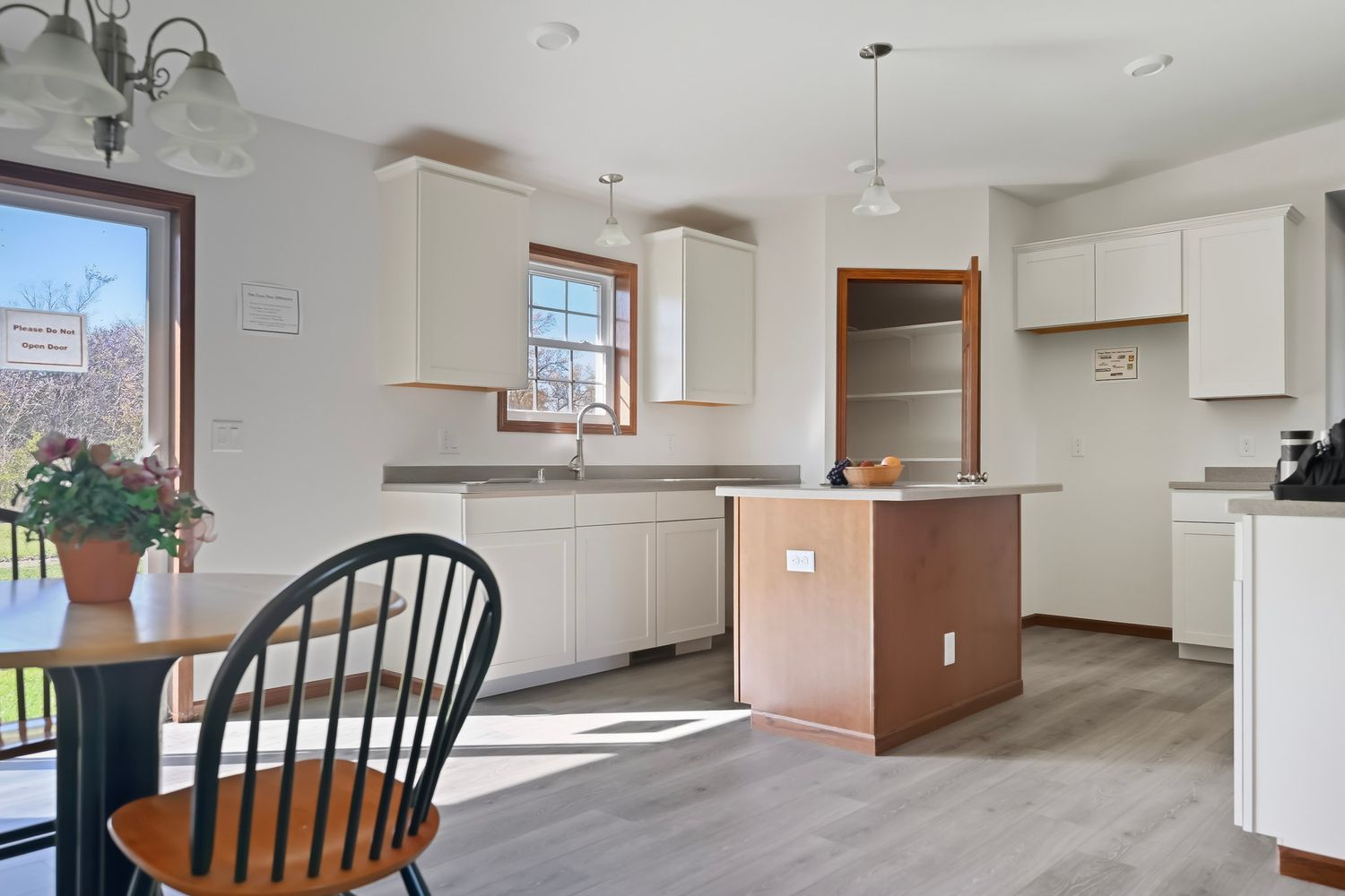 Open concept basement space with white walls, wooden chairs, and natural lighting from windows.