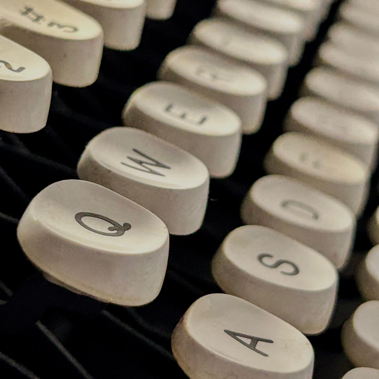 Close-up view of white vintage typewriter keys in a row showing letters and numbers.