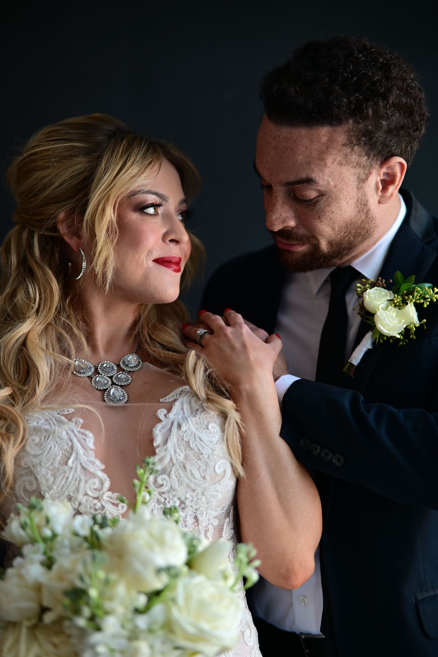 A romantic wedding photo series showing intimate moments between a bride in white lace and groom against a dark background.