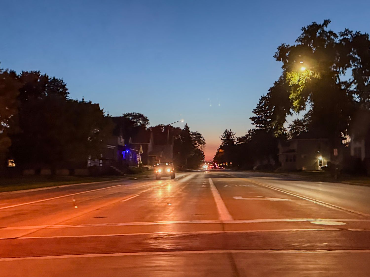 Sunset view of empty suburban street intersection with light trails.