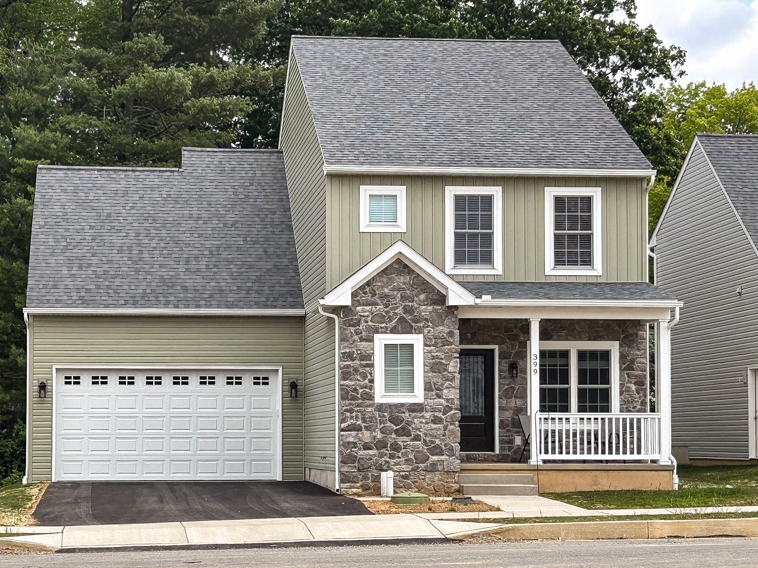 Exterior view of modern suburban homes with stone accents and grey siding in a residential neighborhood.