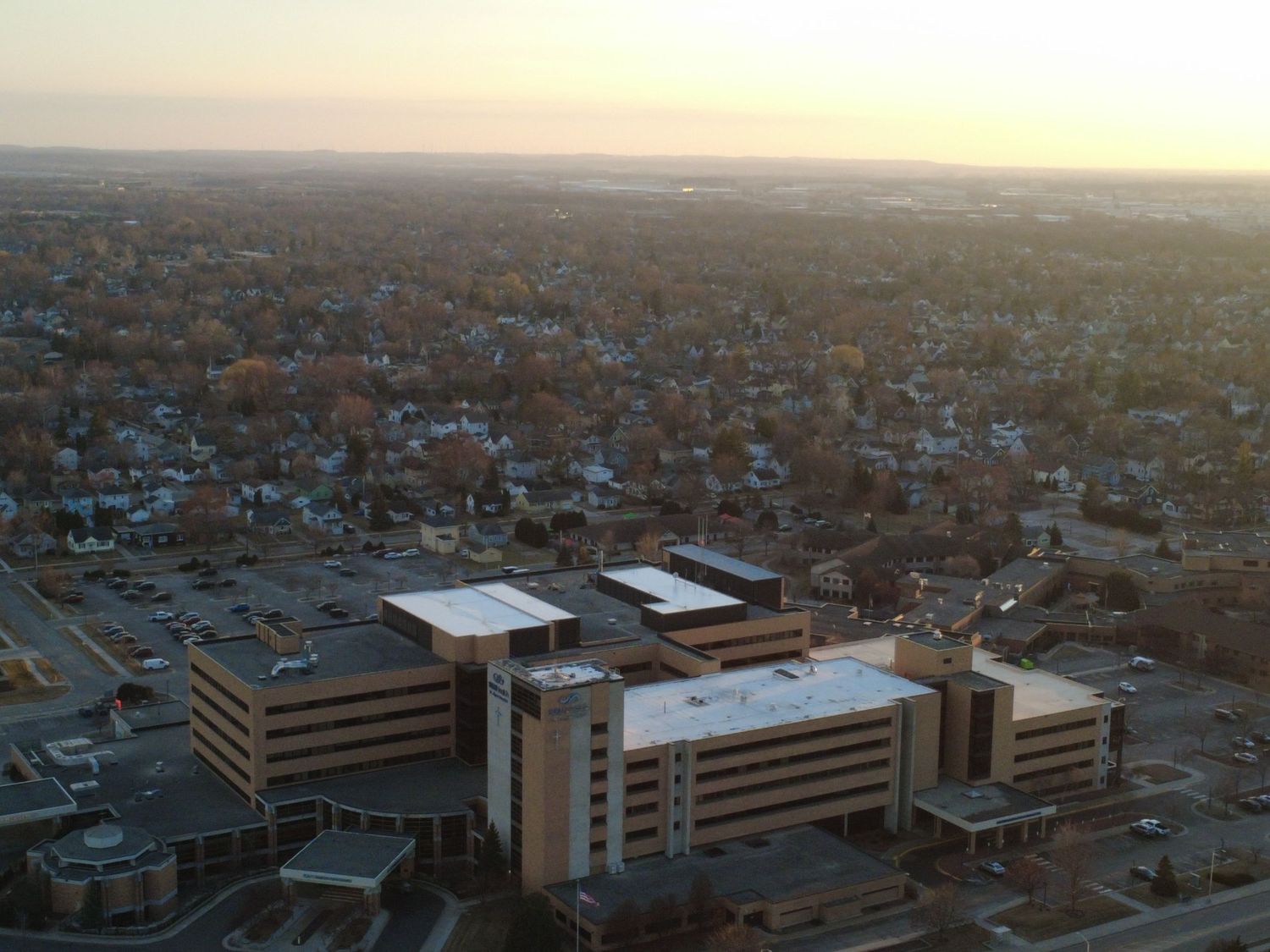 Aerial panoramic view of a suburban cityscape with office buildings and residential neighborhoods at sunset.