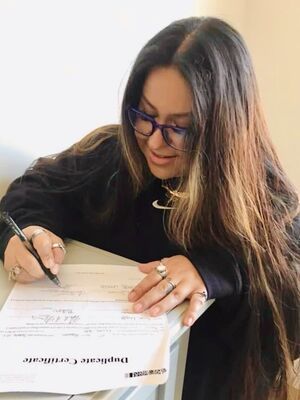 Person in black clothing writing on documents at a desk.