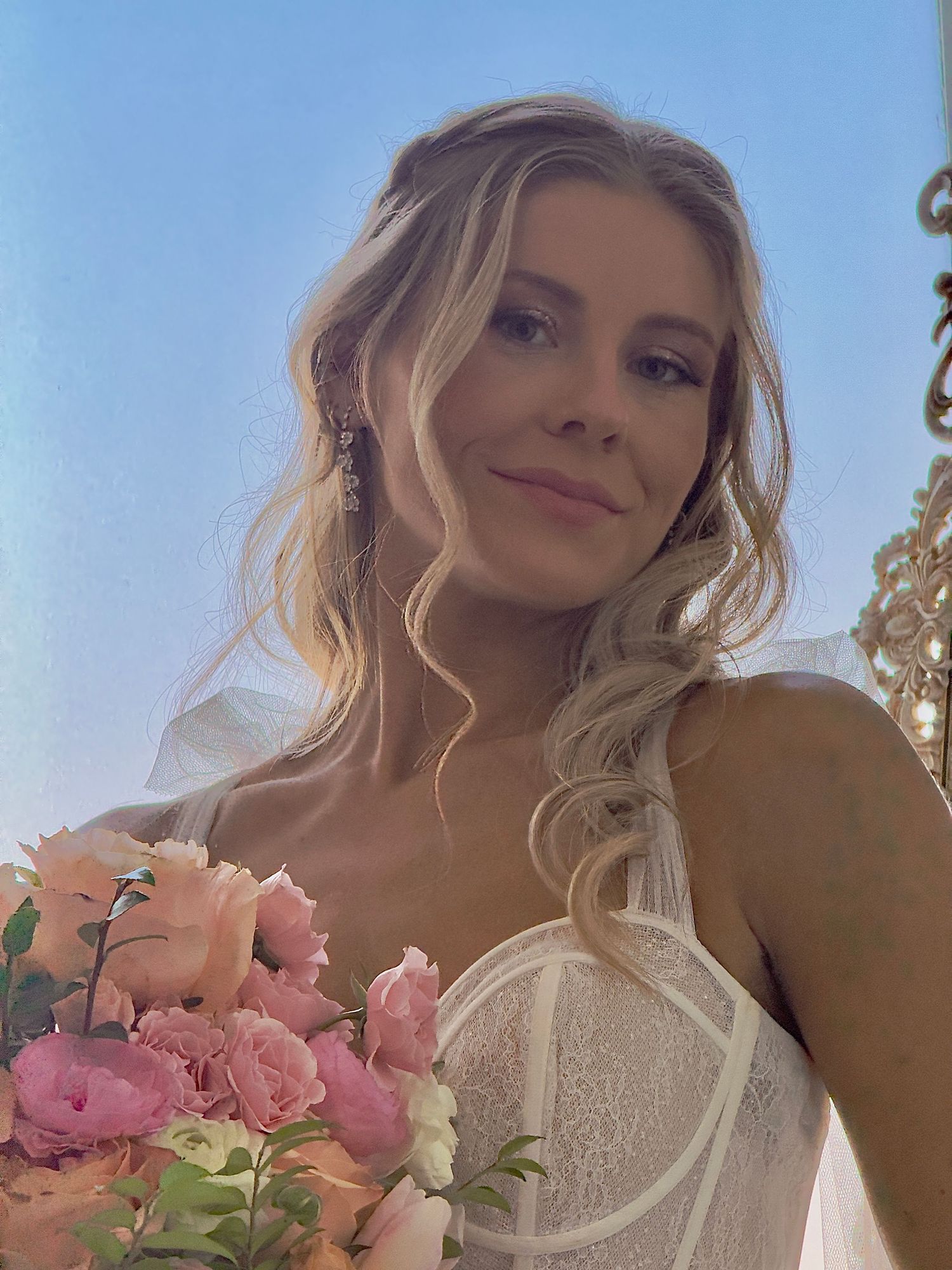 A series of selfie photos showing someone holding a bouquet of pink roses against a bright blue sky background.