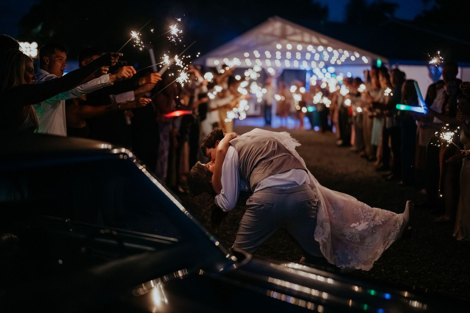 Husband dipping bride during a sparkler exit at night in front of a muscle car in Buckley, WA.