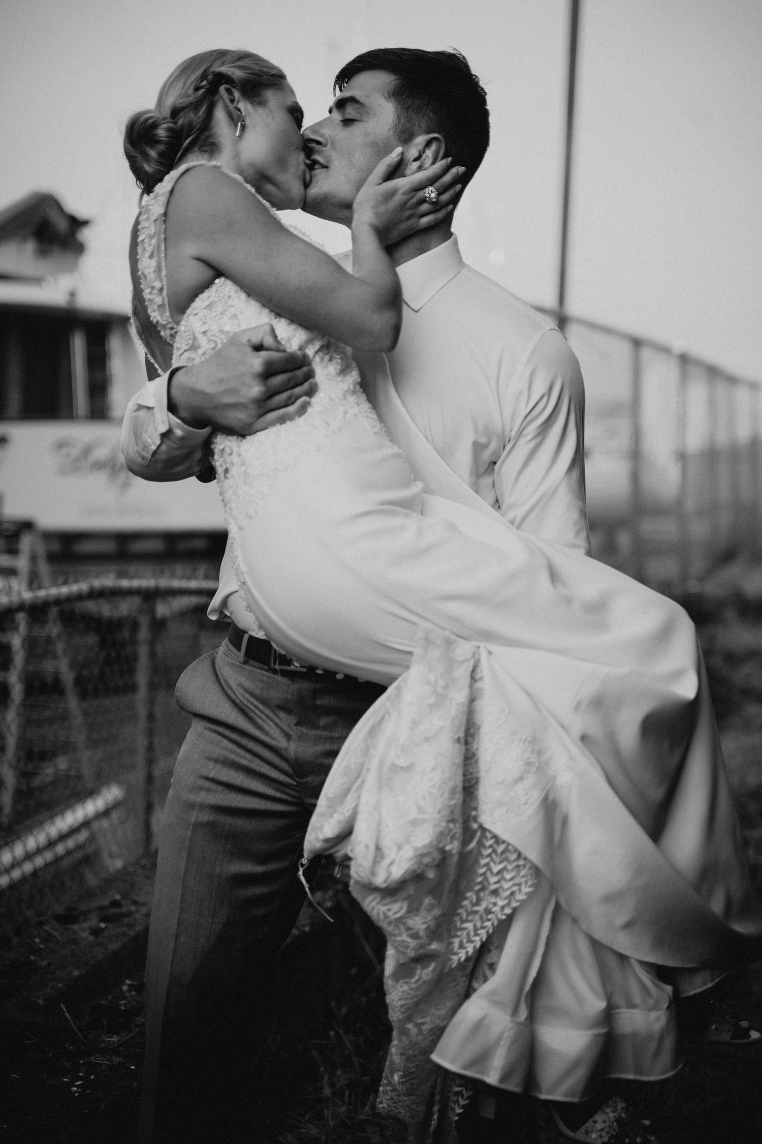 Husband picks up wife for a romantic kiss on their wedding day in Anacortes Washington for their wedding.