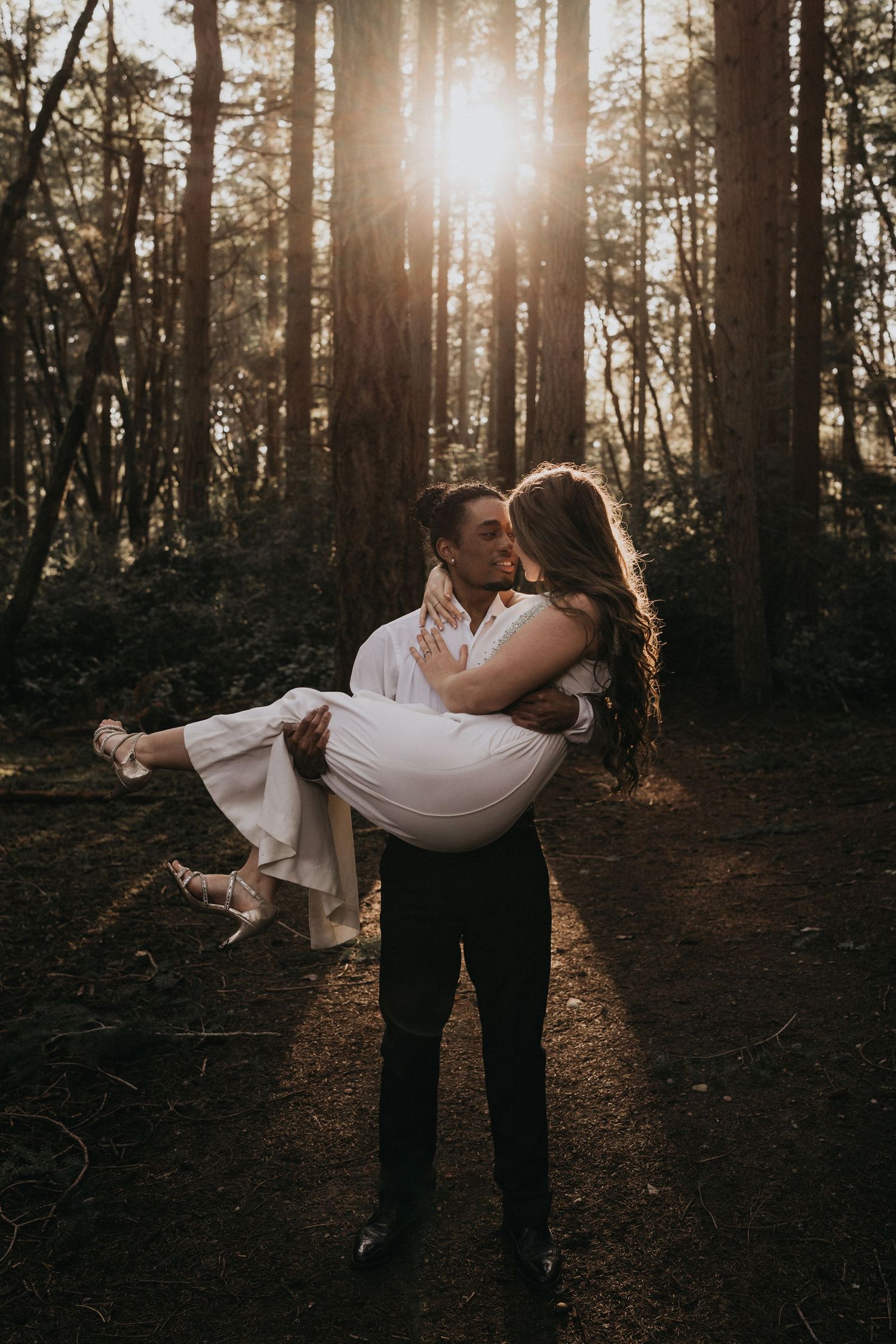 Black man holding white woman in woods at point defiance park for engagement photos in Tacoma WA