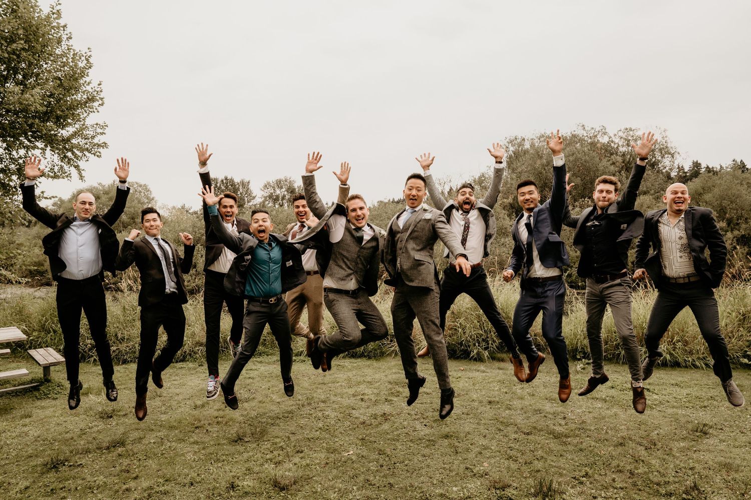 A group of LGBTQ wedding guests jump in the air to celebrate.