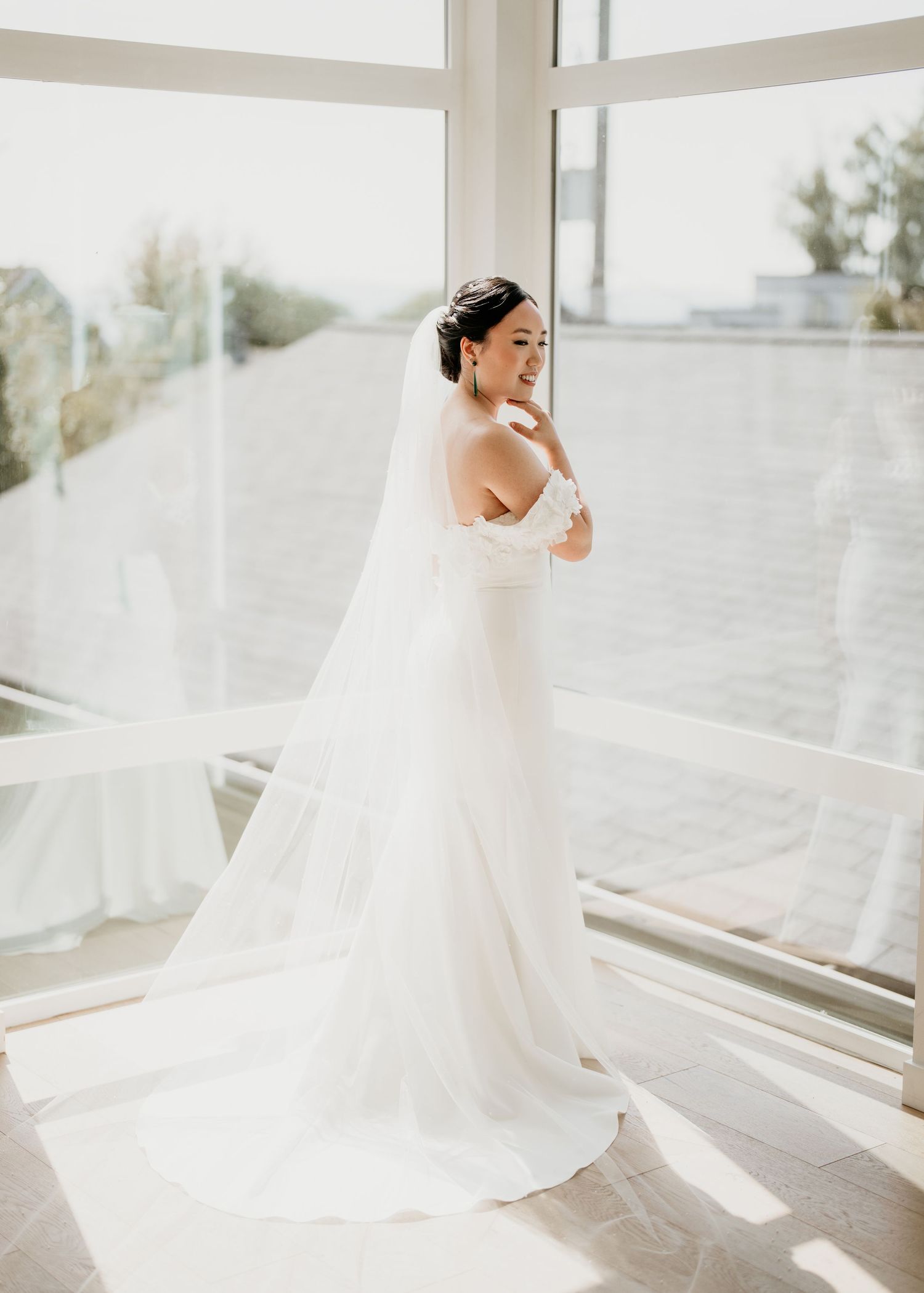Korean bride gets ready by the window in Seattle, Washington before her wedding.