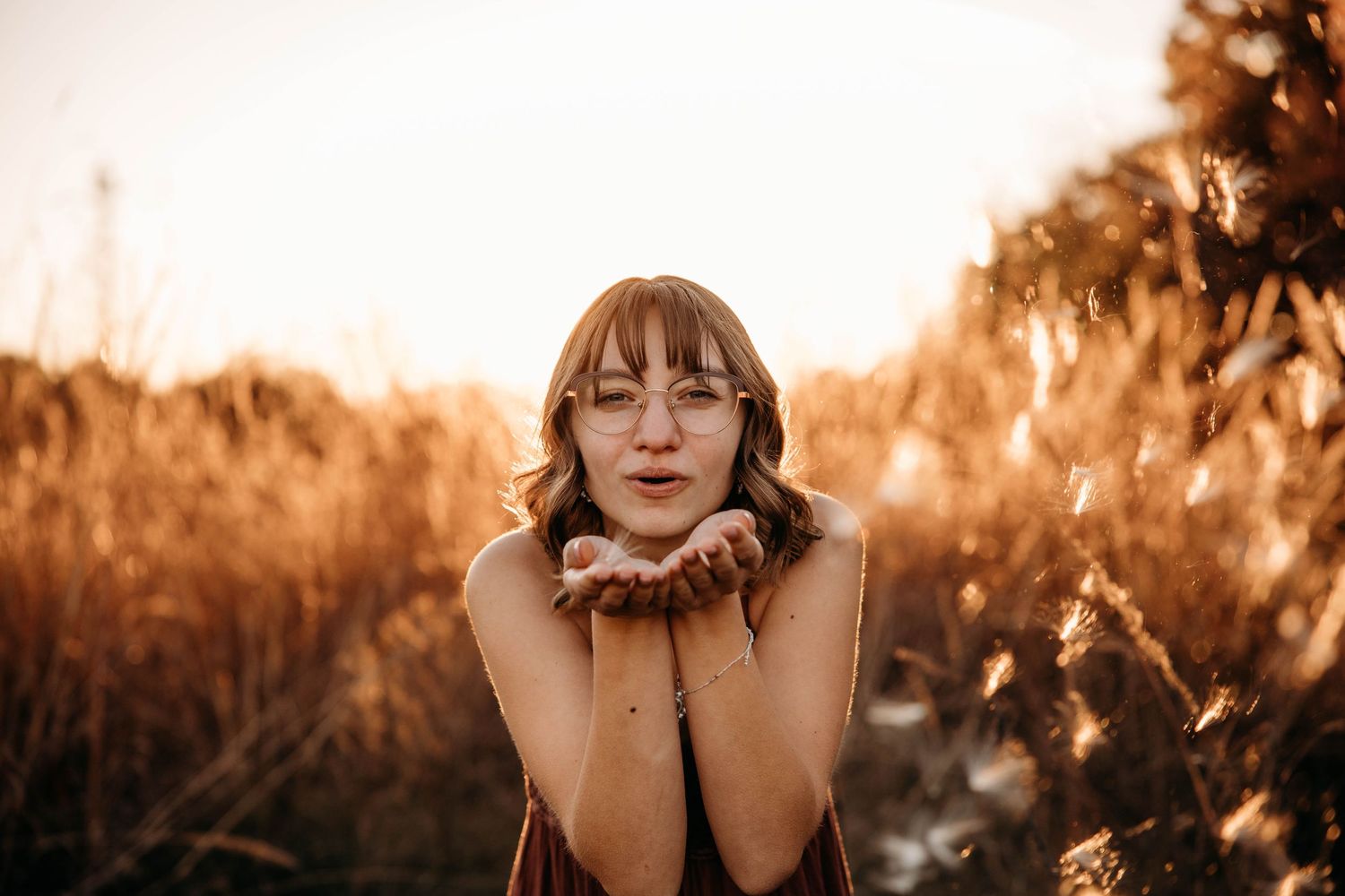 High school senior girl blowing a kiss during a golden hour photo session in a Branson, Missouri field.